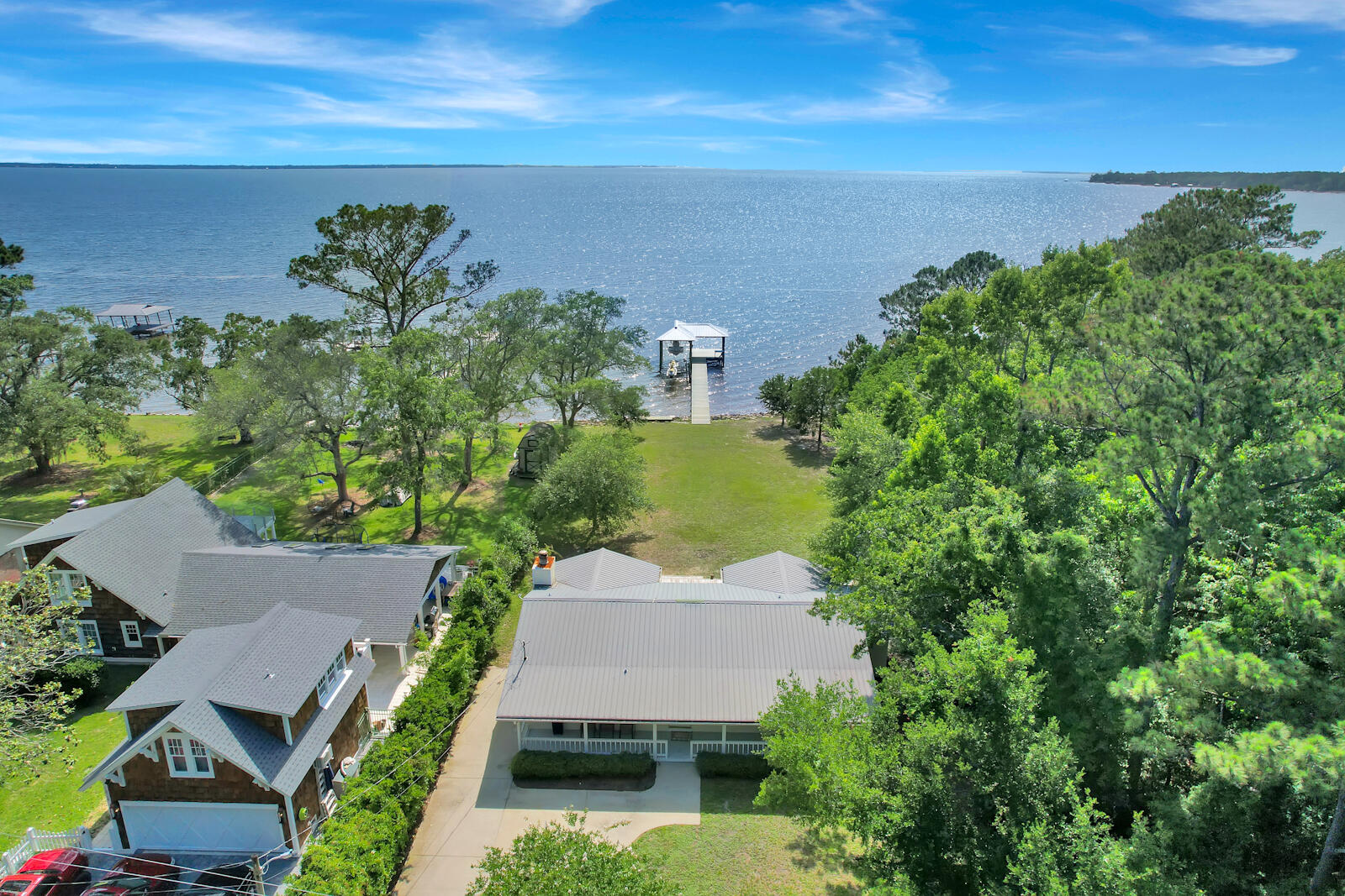 This is the perfect location for bay front living. Located on the highly sought after Bay Grove Road, its no secret this is one of the larger bay front lots. With 83 feet of bay frontage, equipped with a newly reconstructed dock and covered boat and jet ski slips, this location says nothing short of 'boaters paradise'. Enjoy the spacious backyard for your next family gathering or spend your time fishing, accompanied by breathtaking views and the area's captivating sunset. Within just less than 15 minutes from the most beautiful beaches, this bay front property will still allow you to ''get away'' while staying close!