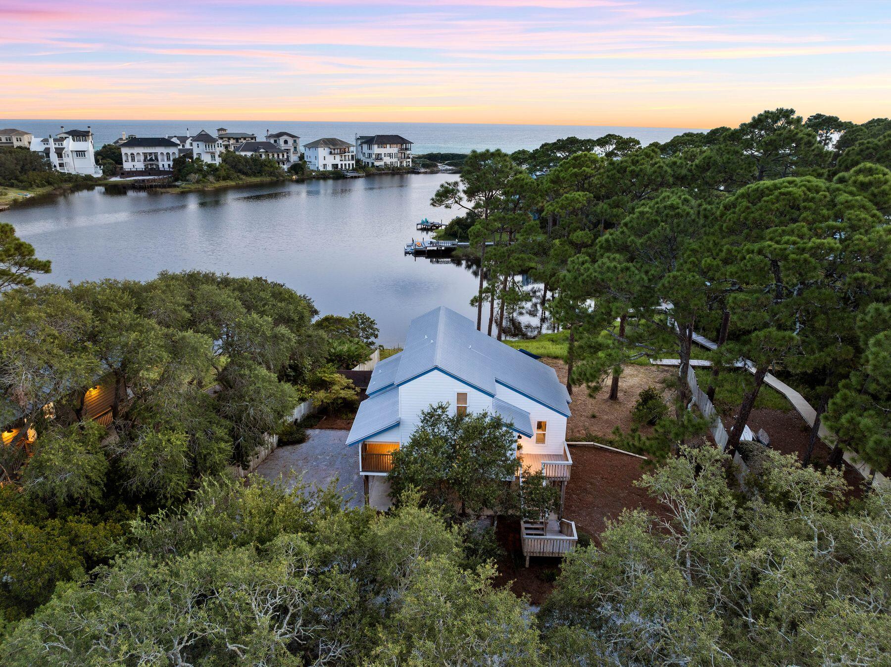This updated waterfront beach house presents a rare opportunity to enjoy lakefront living with amazing gulf views and watersports access. Mature landscaping provides seclusion and privacy along with 100 feet of pristine water frontage on Stallworth Lake. A boardwalk leads down to the water's edge, where the new dock is perfect for fishing or launching paddleboards and kayaks. This rare coastal dune lake provides direct access to the Gulf of Mexico for swimming and beach days. Recently restored to a high standard, this elevated home has a contemporary vibe with new LVP flooring, bathrooms, lighting, and high-end coastal-inspired furnishings. Picturesque views can be found from almost every corner of the home, including the all-new kitchen with chic boho blue cabinets and stainless steel appliances. Enjoy serene views from the breakfast table or take your coffee outdoors onto the back porch and enjoy the fresh sea air. The light-filled family room boasts white shiplap walls and soaring vaulted ceilings with clerestory windows. Also on the main floor is a beautifully updated bedroom with a large balcony offering lake and gulf views amongst the trees. The top floor has two bedrooms, including a fully fitted bunk room, all presiding over stunning lake views. Two full bathrooms have been recently updated with modern white fixtures. This exceptional beach house is in a non-HOA community at the quieter west end of 30A. Occupying an oversized 0.41-acre lot, it has a sweeping circular driveway providing ample space for parking multiple vehicles and leisure craft. There's ample potential for expansion if desired. Local beach access is just 0.4 miles away by road and even closer if you paddle. Neighboring Topsail Hill State Park is a hiking and birdwatching paradise while Seaside, Florida, and Rosemary Beach provide a plethora of restaurants, shopping and entertainment.