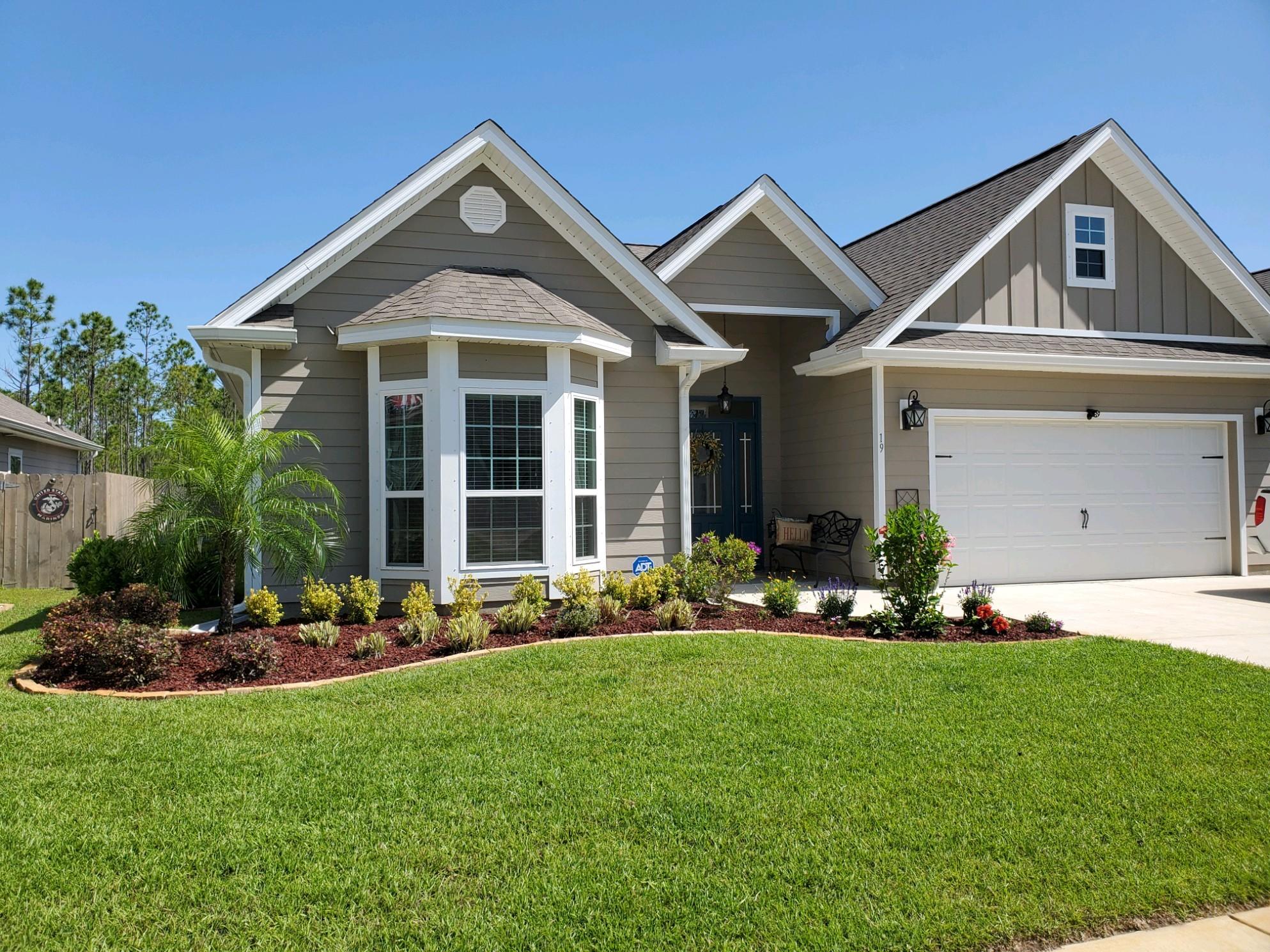 WELCOME HOME to beautiful 19 Eagle Haven Drive.  Colorful landscaping and well maintained exterior lead you to the tasteful covered porch with gutters. When you enter the oversized foyer you will notice the tray ceiling and double crown molding as well as the custom wainscoting. Off the foyer to the left you will find the spacious guest bedrooms featuring a charming bay window and a  guest bath. To the right off the foyer you will find the entrance to the oversized  2 car garage as well as the entrance to laundry.  Going forward you enter the wide open concept living space with a tray ceiling and crown molding feature, dining space and kitchen.  You see nature from the minute you open the front door due to the back of the home being a wall of windows with a view to your oversized lot. In your new home you will enjoy your upgraded plumbing fixtures, stainless steel appliances, LVP throughout main living spaces, upgraded lighting fixtures throughout and upgraded tile features as well.  The Extra Large Main Bedroom brings in light and nature with the large windowss and features a tray ceiling with double crown molding.  Before entering the main bath check out the very large walk in closet that the sellers have customized. The spacious 5 piece main bath has a granite double vanity. Shower features waterfall showerhead as well as a handheld showerhead. The large soaking tub is surrounded by a tile feature as well as a nice sized privacy window that brings in a great deal of natural light. Enjoy the privacy of a separate water closet.
The screened in porch overlooks a spectacular fenced yard that has been landscaped with tropicals that lead you to a custom pergola with retractable awnings and solar lighting. You will fall in love with this turn key gem. Do not forget to check out the family friendly community pool area.