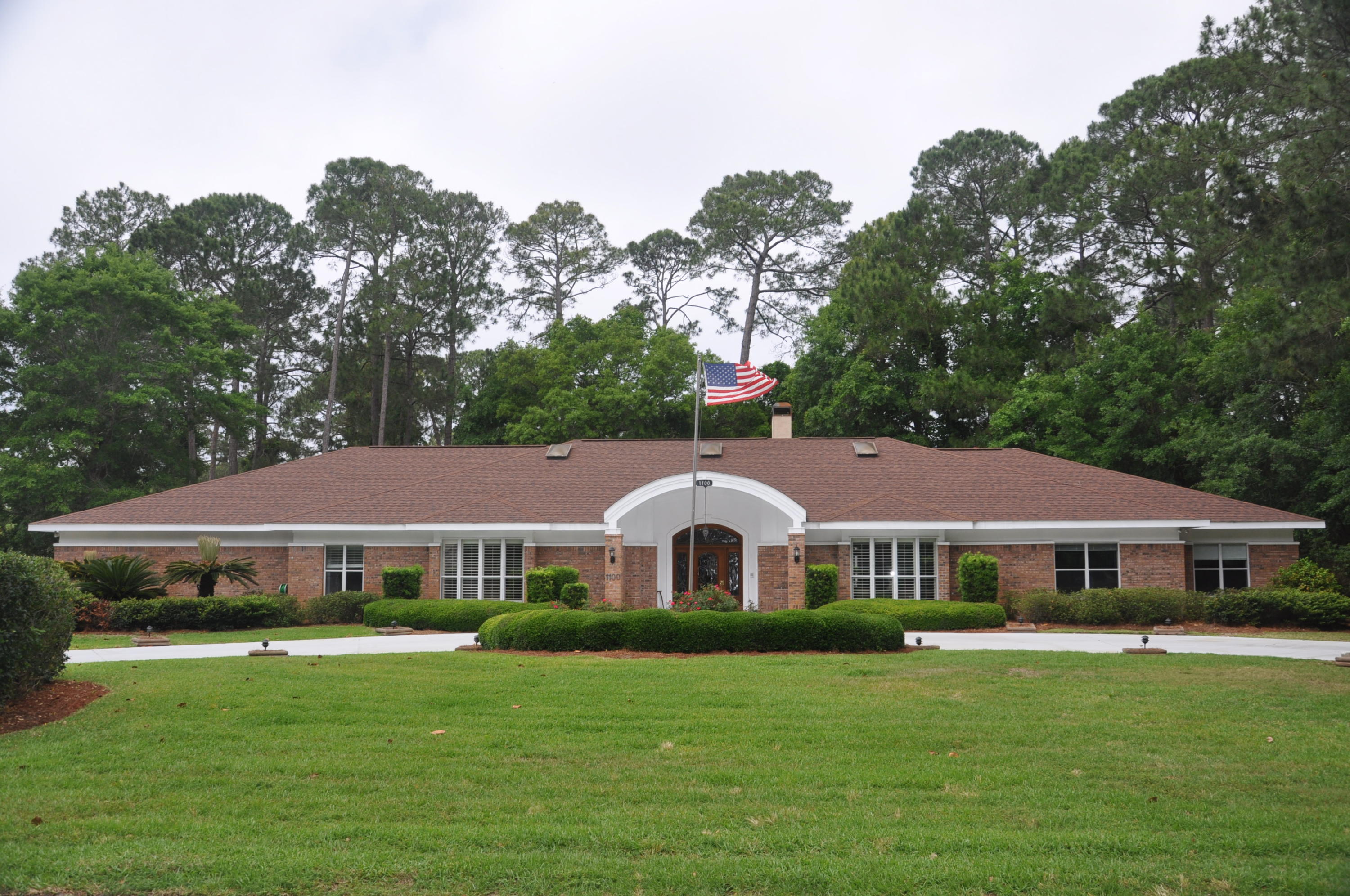Stately, custom built, 5 bedroom/5 bath brick home on double lot in popular Bluewater Bay. Impressive front elevation with circular drive, center flagpole, and side entry 3 car garage. Professionally landscaped all around. Large tiled entry foyer with formal dining room and formal living room on each side. To the right is an entertainment area with wet bar, refrigerator and ice maker. This room leads out to the loggia (outdoor Gallery area) and pool deck. Bright kitchen features granite, double ovens, walk in pantry, generous cabinetry, center island with veggie sink. Breakfast area overlooks the gunite pool. Butler pantry between kitchen and dining room. Split floor plan with large master bedroom with 3 closets, one is cedar lined. also sitting area with French door to pool. Master bath area has 2 walk in closets, double vanity, step in shower, jetted tub and private commode.  Luxury vinyl tile in dining room, living room and lengthy hallway.  Large family room off kitchen is second living area with gas log fireplace.  Many nice interior appointments including trayed ceilings, wainscoting and  crown molding.  5th bedroom offers flexibility of use as an  office, library or room for crafts..   Back bedroom has private bath for guests.  Full hall bath also opens to the loggia and pool deck.  Large utility room with cabinets, sink and commode.    Deep 3 car garage also includes a separate golf cart garage.  Whole house vac for cleaning.  Two HVAC units for comfort control and two new hot water heaters too!!   Good size detached workshop with power and ramp for riding lawn mower.   Beautiful covered pool is heated (gas) and has step spa.  Full landscaping and wooded area behind home provides total pool privacy.  New roof in 2011.  Lawn pump for irrigation.   Termite bond in effect.    An elegant, very comfortable and well maintained home.   A must see property.!!!