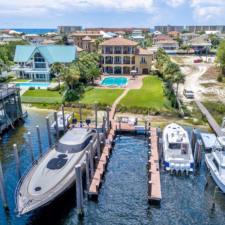 Find your safe harbor with this dream estate located directly on Destin's beautiful harbor! The fabulous large lot boasts a 3-story Mediterranean-style masterpiece, an expansive patio, enormous pool, and phenomenal boat dock configuration. Extensive site work with retaining walls provides favorable lot elevation, so that the home enjoys a nice perch with views in all directions. The same careful attention was committed to the craftsmanship of the interior. The amazing boat dock, which has recently received significant upgrades, includes 4 areas in which to moor vessels: one that will accommodate a boat perhaps as long as 90', a 50,000-lb boat lift, 5,000-lb boat lift, jet ski lift, and much more--a yachtman's paradise! The residence's main living space is on the 2nd floor, including the gorgeous kitchen, living area, a fabulous study/media room/game room with stunning mahogany coffered ceiling and custom polished travertine floors, and the master suite. The kitchen features a Dacor stainless dual gas oven, an electric oven, and hood. In addition to the Subzero, there are 2 refrigerator drawers, 2 dishwasher drawers, and a wine cooler. The custom island offers ample prep space, as well as great views of the harbor. Beautiful Brazilian cherry wood floors enhance the luxury of the master bedroom and its incredible walk-in closet.

Wrought-iron balconies run the length of the 2nd and 3rd floors on the harbor-front, for enjoying the views day and night; plus, there are smaller balconies affording lagoon and Gulf views. The top floor offers 3 bedroom suites, 2 of which have great harbor views, and a storage closet. The first floor includes a living area and small kitchen with beautiful black granite counters. The heated and cooled 3-car garage could also be converted to a bedroom for those desiring a separate first-floor apartment. 

The stunning 25' x 50' salt-water pool can be heated and features 2 wading areas and a hot tub. There is both a heated and cooled 2-car garage and an additional garage area for pool equipment, water sports toys, an icemaker, etc., as well as a workshop or "tack-room"--everything you could desire to enjoy the nautical lifestyle of Destin, Florida!