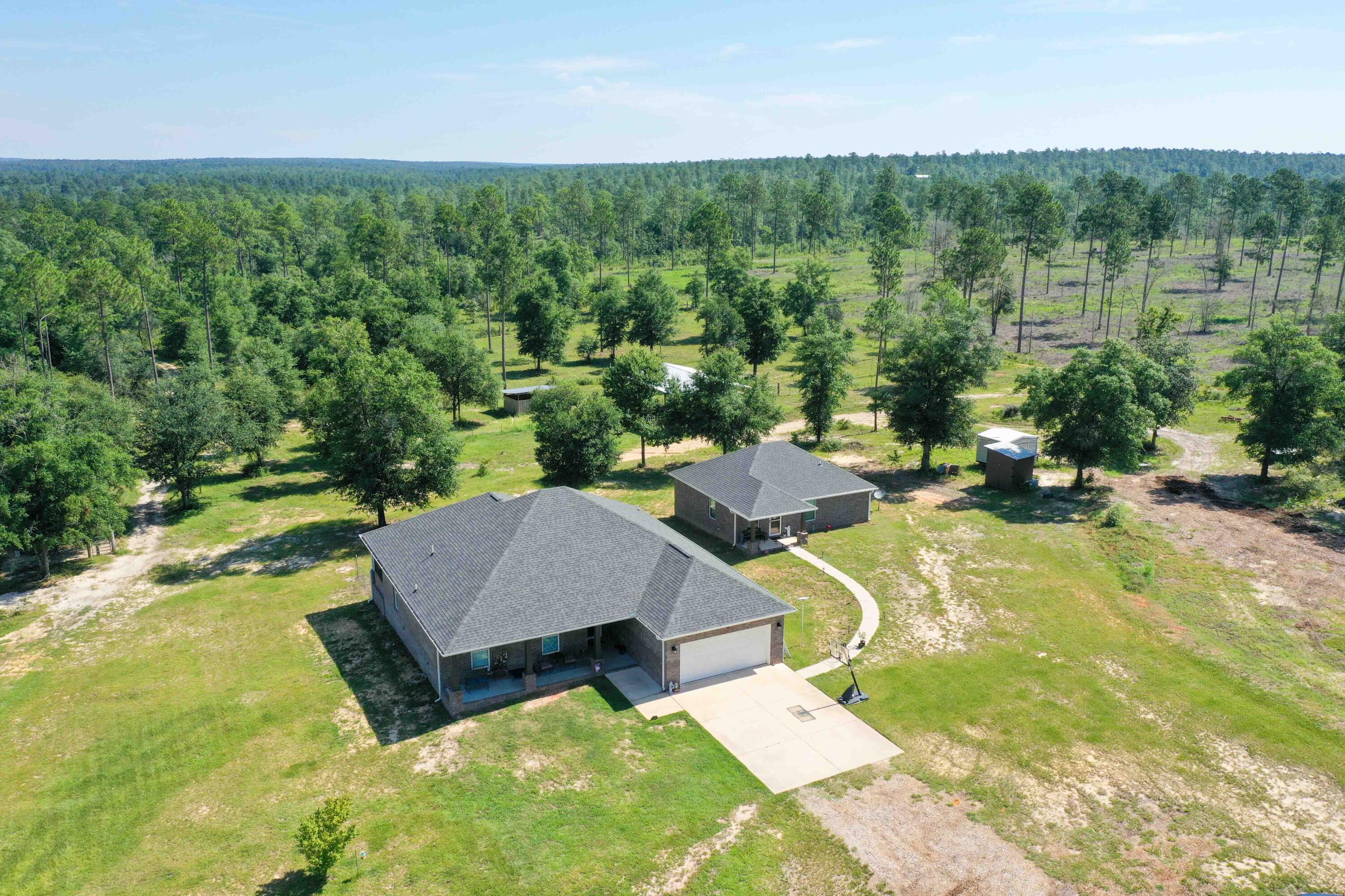 TWO HOUSES a Green house a pole barn and more! Seller willing to buy rates down for a qualified buyer using our preferred lender!  This was an income-Producing Multi-Family Farm on 12.5 Acres with a 1705 sqft main house and a 952 sqft guest house! Towards the back of the property you will find a small creek. The property is close to Blackwater State Forest and the popular river spot Cotton Bridge and not in a flood zone!
Welcome to your dream multifamily rural escape offering a rare opportunity for multi-generational living, rental income, or homesteading with everything you need already in place. The main house features 3 bedrooms and two bathrooms and large porches. The full guest house features 2 bedrooms , 1 full bathroom and one half bathroom and its own laundry room as well. The quality craftsmanship and functional design includes Unique touches like power outlets in soffits (great for holiday lighting) and gutter drainage away from the home. Inside there is custom cabinetry throughout with touches like soft close cabinets, a pull-out spice rack, enjoy the (LVP) flooring throughout with porcelain tile in bathrooms, Soundproof walls around the laundry room for added comfort .Combine this with  MLS 979585 to create even more of a multi family homestead or farm.