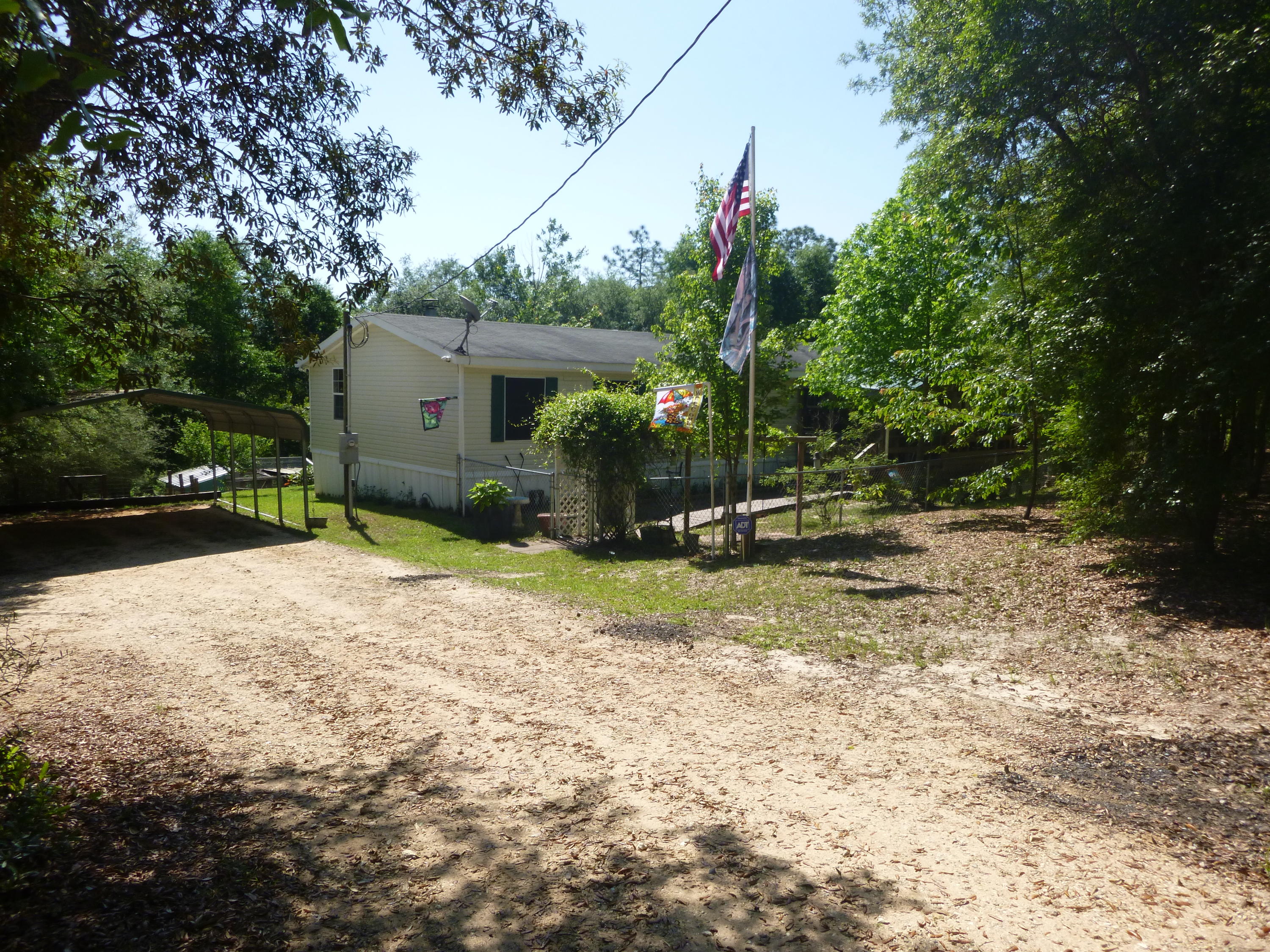 TURN KEY! Manufactured home on over 4.5 acres. All fenced with 4 ft privacy fence up front along with entrance gate. Home has large front porch, split floor plan, wood/ carpet flooring, and ADT security system. Skirt around the bottom of home is being replaced. Master bedroom has solar panel screens, walkin closet along with a study loft before you enter the bathroom. Master bathroom has two sinks separated by Jacuzzi. Two of the other three bedrooms do have walkin closets. One room is being used as an office with a built in desk. The room without the walkin closet has a built in bookshelf. There are two living rooms one by the front door overlooking porch and yard. The other has a wood burning fire place. The kitchen is very open with also a solar panel screen, reduces the electric bill. Outside there is a 2 car carport, roughly a 19x22 shed, chicken coop, and a dog pen. The front porch has an area that is chain linked for smaller dogs. This property has both city and well water, your choice. HOA fee is for the road maintenance. This is a beautiful piece of property close to the city and a short drive the beaches. Booking your showing today! Seller is offering a one year home warranty. Do Not miss out on this piece of country. There are many neighbors that have horses and livestock so bring all animals. Big training facility up the road for horses.