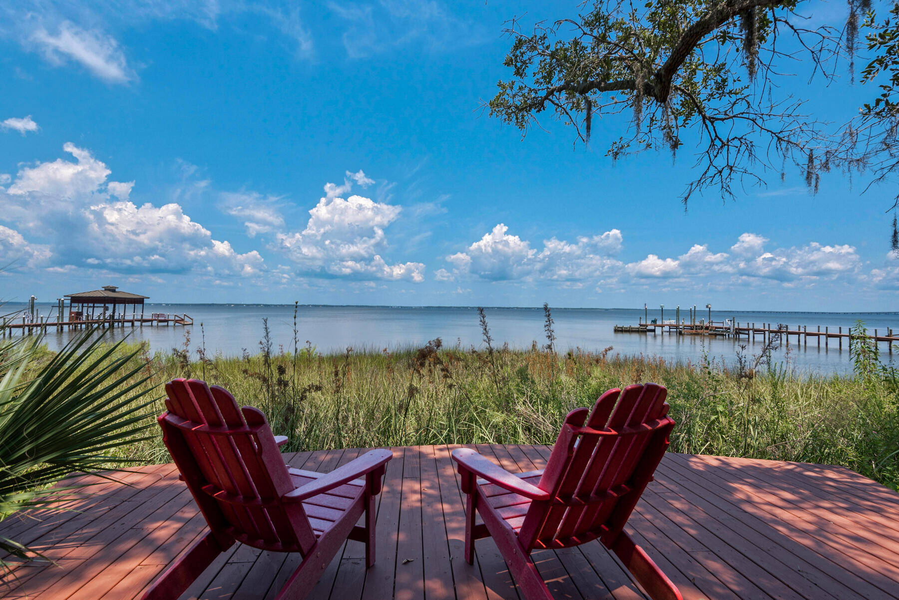 UNDER CONTRACT WITH  72 HOUR KICK OUT CLAUSE IS IN EFFECT.  250+ feet of waterfrontage, 6800+ square feet of heated and cooled spaced make this offering an incredible deal for a buyer.  Five total bedrooms, two are master suites on the 2nd floor, one master suite is on the 1st floor. 
Two additional bedrooms are also on the first floor with two baths.  The main kitchen, living area, dining, den, wet bar and laundry are on the 2nd floor. First floor offers an additional living-dining-kitchen and laundry. Boat dock with boat lifts - jet ski  lifts.  There is a workout room/gym or office space located just outside the first floor screen porch. There are 2 screen porches on the 2nd floor one with a summer kitchen and fireplace.  Two lengthy driveways allow for RV's or boat parking.  No HOA.