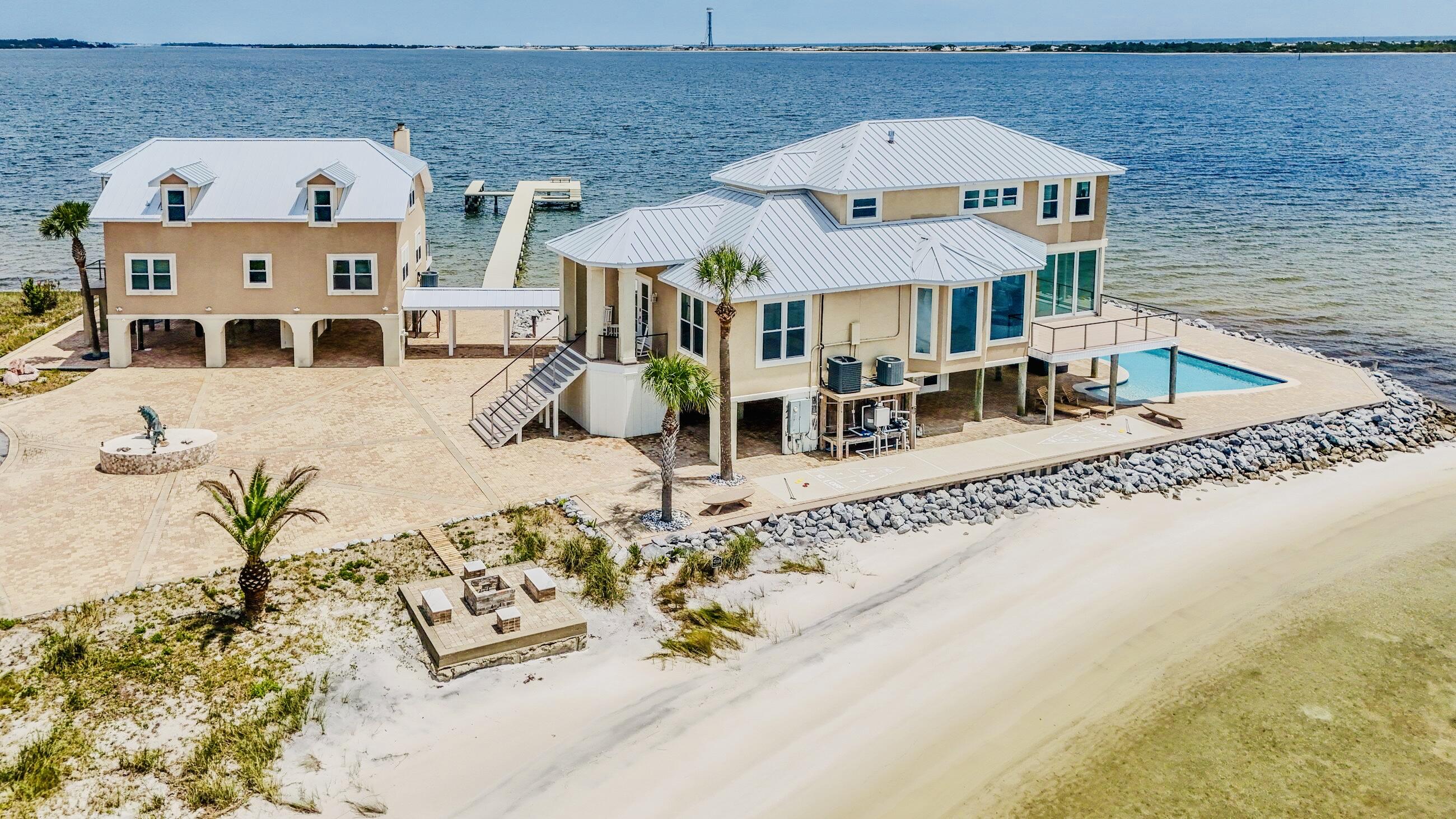 WRAP-AROUND WATERVIEWS!  PRIMARY HOME, GUEST HOUSE, POOL, BOAT DOCK & PRIVATE BEACH! Introducing 320 Sunny Drive, THE Crown Jewel of Emerald Coast Waterfront with over 180-degree views from the Santa Rosa Sound to the Gulf.  The 3B/2.5B main residence boasts views that will absolutely take your breath away!  The first floor open concept is an entertainer's dream, while the second floor is a relaxing primary retreat. Even the separate 3B/2.5B guest house features water views from almost every room.  The expansive waterfront pool patio is surprisingly secluded, with paved paths leading to the private beach, boat dock (2018), fire pit, shuffleboard and chess. Parking is abundant and Tesla ready. Inside Sandy Pointe, a gated community, 320 Sunny Drive is a MUST SEE!