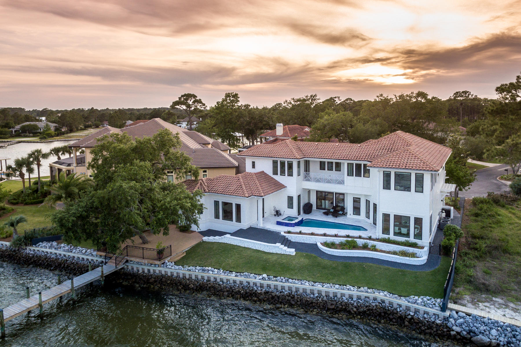 Behind the gates of this private Grand Cove estate, you will find a tranquil and breath-taking setting in this Geoff Chick designed home. With 135 feet fronting the Choctawhatchee Bay, this 4 bedroom, 4,516 sq ft home offers a lifestyle filled with beautiful sunrises and days of boating and an unlimited bounty of fishing from the Bay or just off the deep water dock which can accommodate up to a 50 foot boat. The pool court bathed in custom tumbled marble, serves as the backdrop for lazy days by the heated, salt-water pool or cool nights in the spa stargazing over the Bay. Two master bedrooms captivate picture window views of the waterfront and gives families the flexibility of one on the first floor and one on the second floor. Both master bathrooms showcase soaking tubs to relax alongside the quiet sound of waves lapping the shoreline.   
The kitchen is a chef's dream with an expansive island and
 waterfall quartz countertop and a wet bar. The open concept great room welcomes the sunrise each day and the fireplace flanked in a floor to ceiling quartz mantle warms you on cool, crisp nights.  Upstairs, a midnight kitchen serves as the perfect spot to grab a cold drink from the fridge or brew a cup of coffee to start your day.
Custom Brazilian walnut flooring fills the living spaces throughout the home. A walk in wine cellar offers abundant space to store the perfect wine collection.  A tankless water heating system and water softener provide the ideal conveniences to enjoy.  Looming signature oaks, pine and flowering magnolias soar above this home, casting just enough shade to cool the hot summer days.  Make sure you see the video tour of this beautiful home!