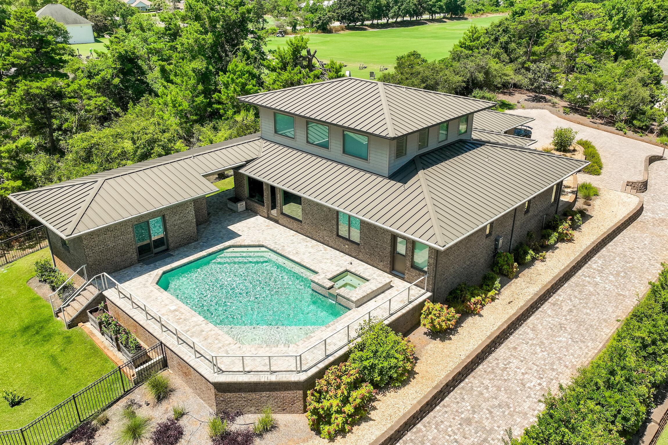 Nestled in the prime west end of 30A, this exceptional custom-built, mid-century modern home offers a rare blend of coastal luxury and serene living. Situated on a spacious 3/4 acre lot boasting one of the highest elevations (50-55 ft) on the coast, this property offers unparalleled privacy. Adjacent to Santa Rosa Beach Golf Course, you can enjoy direct access to the driving range & clubhouse, making it a haven for golf enthusiasts. The elevated position not only offers breathtaking views of the surrounding natural landscape but also ensures a sense of exclusivity and tranquility. Whether enjoying the expansive outdoor spaces or cozy fire pit, relaxing by the heated saltwater pool & spa, or exploring the pristine beaches nearby, this 5 bedroom home epitomizes the allure of coastal living! The exterior is a testament to both style and durability, featuring brick construction, a standing seam low profile metal roof, and high impact (Anderson) glass windows throughout. A multi-tier paver stone driveway leads to a spacious 2-car garage and offers ample parking with 8+ exterior spaces, making this a prime home for entertaining. Inside, the home features a sophisticated mid-century modern design with clean lines, expansive windows that flood the interiors with natural light, an open floor plan and luxurious finishes throughout. Architectural details include a stunning stained maple hardwood staircase and fine custom cabinetry by Elmwood, complemented by Quartz countertops, upscale stainless steel appliances & gas range in the galley style kitchen. The island is ideal for casual dining with unique pedestal lighting above or enjoy a more formal setting in the dining area. The spacious first-floor primary suite overlooking the pool is a quiet oasis, featuring a luxurious ensuite bathroom with a large soaking tub with nature views, steam shower, and direct access to the outdoor hot tub. Additional highlights include a walk-in storm shelter room, a whole house generator for peace of mind, and a tankless Rinnai gas hot water heater ensuring comfort and efficiency. Upstairs, an additional living area and two guest bedrooms provide ample space for family or guests, while a fifth bedroom in the pool house offers privacy and convenience with its own full bath. 

Its proximity to the beach, Gulf of Mexico, and the rare coastal dune lake, Oyster Lake, presents endless opportunities for outdoor activities such as paddle boarding, kayaking, and fishing. Residents also have the option to join the prestigious Santa Rosa Beach Club, enhancing their coastal lifestyle with exclusive amenities and social opportunities. Surrounded by natural beauty and conveniently located near dining and entertainment options like Stinky's Fish Camp, Shunk Gulley, and A Perfect Pig, you can indulge in both serene surroundings and vibrant local culture. Mere minutes away, Topsail Hill State Preserve offers hiking trails and 3 miles of beach to enjoy, while the inviting atmosphere of Kith & Kin coffee shop provides a charming spot to relax. The absence of HOA restrictions in this non-rental community allows for freedom in personalizing and enjoying the property. Whether as a second home retreat or a year-round residence, this is a meticulously crafted sanctuary where luxury meets convenience in one of the most desirable locations along Florida's Gulf Coast.