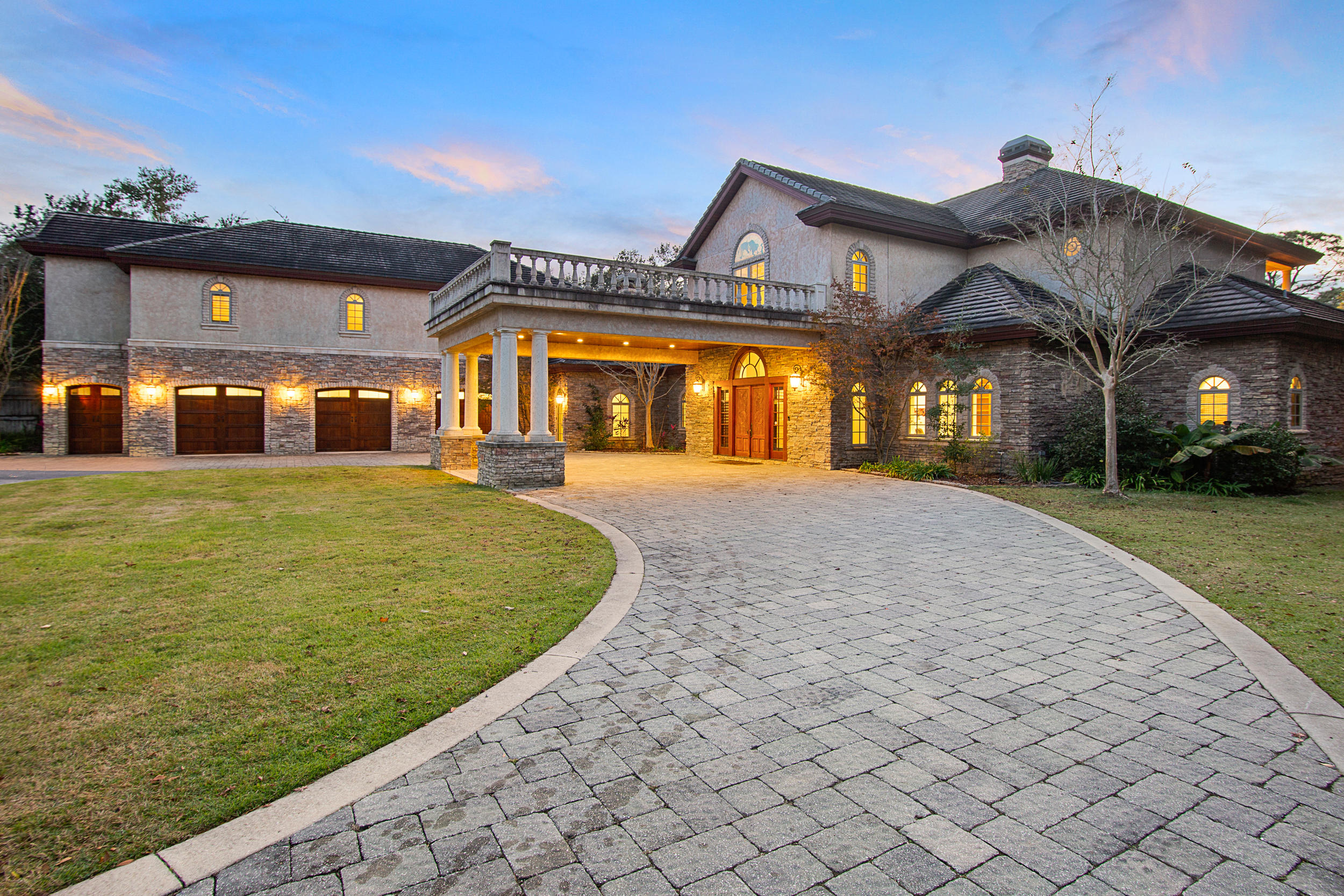 A rare opportunity to own a 2.5-acre estate on the water in a coveted location with no HOA, no restrictions. The live oak-shaded private entrance, past a fenced pasture and horse stable with two stalls and tack room, gives way to a circular drive with covered porte-cochere entrance. Plenty of parking for guests or nautical toys in the 3.5-car garage or the pavered drive. Hand-carved double teak doors open to a grand foyer with sweeping staircase and whitewashed Craftsman-style columns. Just beyond the entrance and past a chandeliered sitting room with wood-burning fireplace is a 2000 sq ft limestone patio, an expansive lawn, and 200 linear feet of shoreline on Hewitt Bayou with a private dock and covered boatlift.  (Continued...) The main house consists of a cavernous living/dining/kitchen space with a second wood-burning fireplace as a focal point, a chef's kitchen with double ovens, a six-burner gas range with copper vent hood, a walk-thru pantry leading to a wine storage room and a screened summer kitchen beyond, a ground floor master bedroom with sunset views, office with floor-to-ceiling bookcases, weight room, a half bath and two laundries. The upper story, accessed by the grand staircase or by wood-paneled elevator, consists of two spacious bedrooms with en-suite baths connected by a carpeted bridge under soaring wood beams and flanked by massive chandeliers. Both bedrooms open west onto a broad columned balcony overlooking the lawn and bayou. The east wing of the house has its own access stairs with four additional bedrooms, two full baths, and a full kitchen and living space. The home is of reinforced concrete construction and is in an "X" flood zone with an elevation of over 10 feet. A whole-house generator provides continuous power and peace of mind during the occasional storm to all 8,852 square feet of heated and cooled space. Coastal lifestyle features include a newly installed heated swim spa, a three-slip floating jet ski dock, a batting cage and, for the very limber, a Ninja Warrior obstacle course. Bring your horses, your boat, even your mother-in-law. This property has plenty of room for all of them.