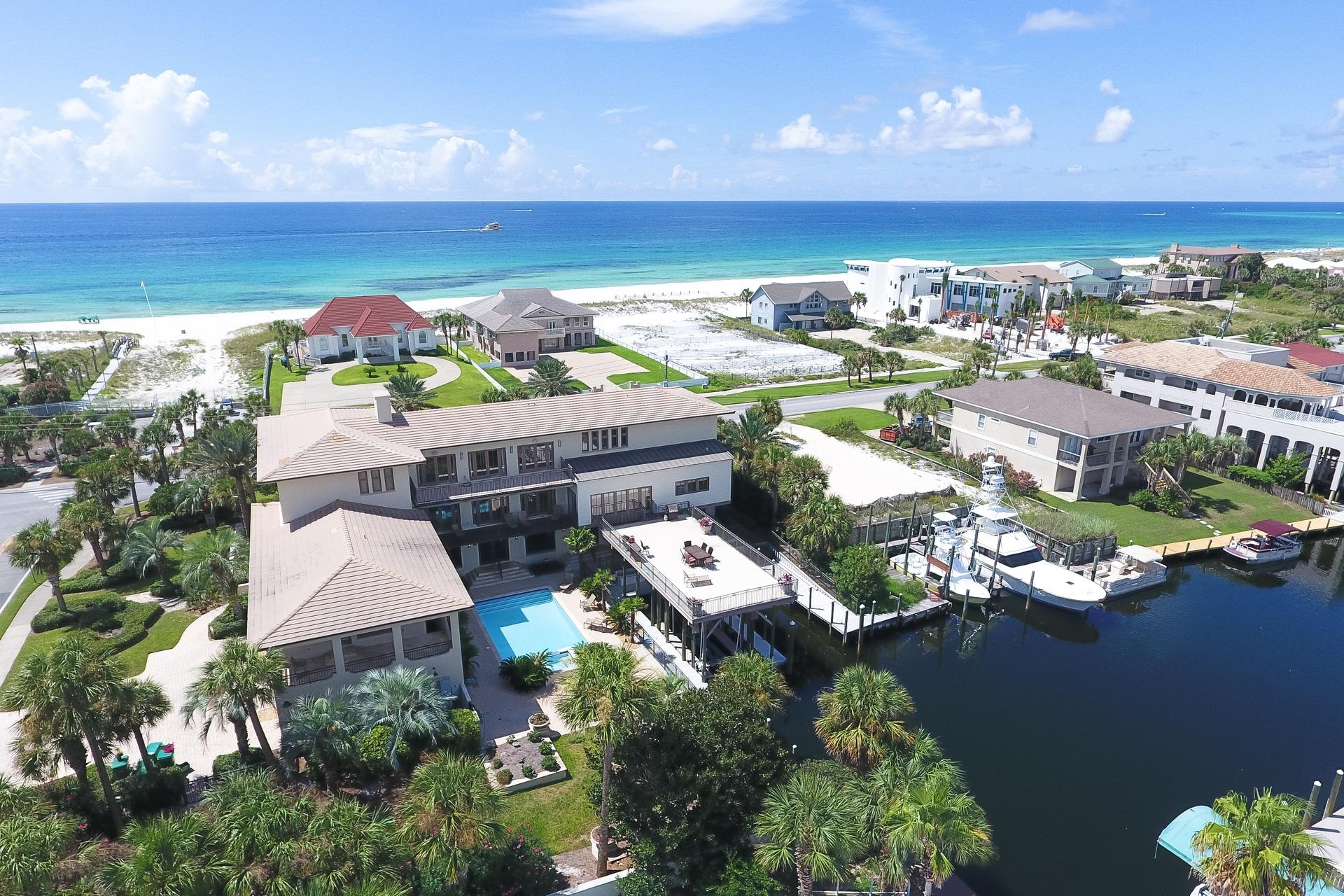 Masterfully built cast & pour concrete construction prominently situated on one of the largest residential home sites on Holiday isle with 90' of deepwater harbor frontage paired with expansive gulf views and exceptional proximity to the beach. This home has been recently updated with coastal contemporary decor as well as a floor plan modification to bring the total bedroom count to eleven in order to optimize short term rental income with projections exceeding $375,000 annually with current actual income exceeding $370,000 year to date for 2018. As of 2018's 4th quarter, there is already $258,000+ booked for 2019. Experience an unparalleled waterfront lifestyle with two spacious covered deepwater boat slips easily accommodating a captain's choice vessel all accessible to navigable waterways promptly leading to Destin's famous East Pass, Crab Island as well as the emerald green waters of the Gulf of Mexico.
This home is outfitted as the ultimate beach escape and can be utilized as a gathering place for corporate events, multi generational family retreats or a primary/secondary residence. Notable interior features include a 14 seat in-home movie theatre, sauna, game room, private pool with spacious outdoor decking and water feature as well as a chef's kitchen featuring private access from staff quarters complete with wood paneled appliances allowing for a flush aesthetic and ample cabinet storage topped with beautiful granite countertops all specifically designed for entertaining. The sprawling master suite is primely situated on the Eastern boundary of the home and enjoys direct unobstructed gulf views as well as two large ensuite bathrooms, each well equipped in addition to two large walk-in closets. Other notable features include a private elevator that services all three levels, multi-car garage with side entry and ample outdoor parking. The expansive main living area includes a custom bar all open to the covered front and rear porticos. The formal dining room is framed by a multitude of windows allowing an abundance of natural light and a continuation of gorgeous gulf views. The strategic positioning of this home was realized in order to capture forever views as it is adjacent to beach access. This property is also located within close proximity to all of Destin's world class shopping, dining and entertainment.