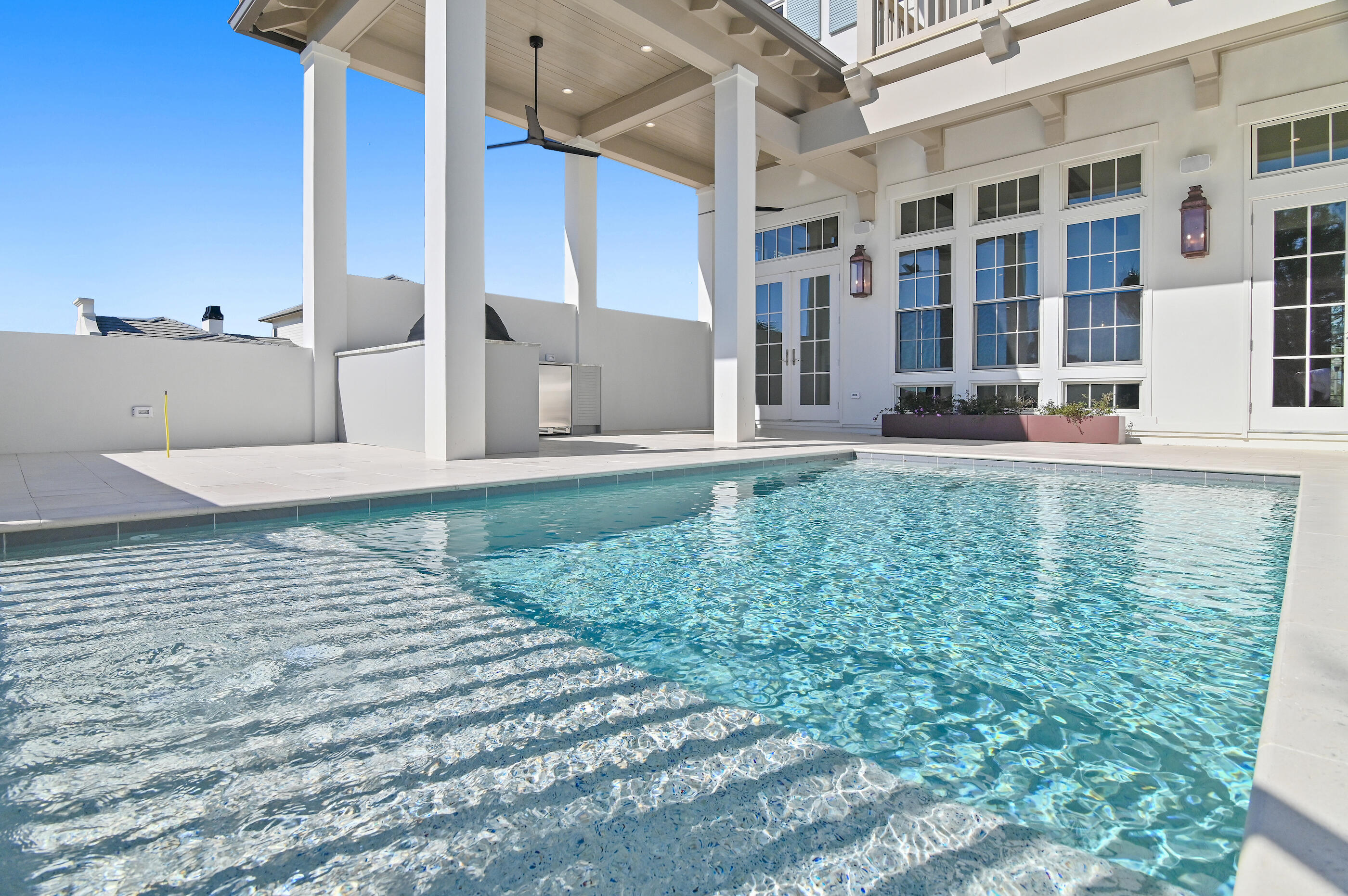 Less than a mile from the beach, this breathtaking new construction home delivers exceptional luxury and striking attention to detail. Welcome to Tradewinds--the newest enclave within Regatta Bay--featuring 54 exclusive homesites inspired by refined West Indies and Dutch-Caribbean architecture .This exquisite residence offers over 3,700 square feet of climate-controlled living space with 4 bedrooms, 4 full baths, and 2 half baths. Designed for seamless indoor-outdoor enjoyment, the home centers around a private outdoor oasis complete with a summer kitchen, hot tub, firepit, and an Alys Beach-inspired pool, creating an ideal setting for both relaxation and entertaining. Inside, the open-concept layout immediately impresses. The expansive living room is anchored by a custom fireplace and flows effortlessly into a chef's kitchen featuring quartzite countertops, a large island, premium appliances, and a spacious butler's pantry. The first-floor primary suite offers serene views and direct access to the outdoor living area. Its spa-like bathroom includes dual vanities, designer lighting, a custom-tiled walk-in shower, and a luxurious soaking tub. A generously sized walk-in closet features custom shelving and built-in his and her storage. Also on the main level are a stylish powder room, a wet bar, and a private guest suite with its own bath. The second floor features a large bonus room with an additional wet bar, two guest suites with private baths, a flexible storage or multipurpose room, and an oversized balcony perfect for enjoying evening breezes. Built by Legendary Home Builders, utilizing only the finest materials and high end finishes such as: wind and impact resistant windows, wind and impact rated doors, insulated wind and impact rated garage doors, insulation in all interior walls for energy efficiency, sound proofing insulation between floors for sound barrier, stainless steel door hinges, custom wood shelving in all closets, Kohler plumbing throughout, custom solid wood cabinetry throughout with soft close hinges, surround sound, smart home technology customizable for homeowner, led lighting throughout and so much more! This extraordinary home captures the essence of modern coastal luxury beautiful, functional, and just moments from the beach.Regatta Bay is a serene, gated community that seamlessly blends golf and boating, offering a lifestyle that is truly unparalleled! The essence of the Regatta Bay Lifestyle revolves around convenience, allowing residents to easily access numerous enjoyable destinations within minutes via golf cart, including the beach! Within the community, residents can indulge in golf, swimming, tennis, pickleball, parks, playgrounds, the Regatta Bay Clubhouse, Legendary Marine, and Legendary Yacht Club. Furthermore, Regatta Bay features a private road that leads directly to the Destin Commons, where an array of popular retail stores for both men and women awaits, alongside a diverse selection of restaurants, Whole Foods, Bass Pro, Lowes, an AMC movie theater, and Uncle Buck's Bowling-all easily reachable by golf cart. Regatta Bay is centrally located offering easy access to the airport and only a few miles from Northwest Florida's finest hospital. Schedule your private tour today and experience the elegance of Regatta Bay living.