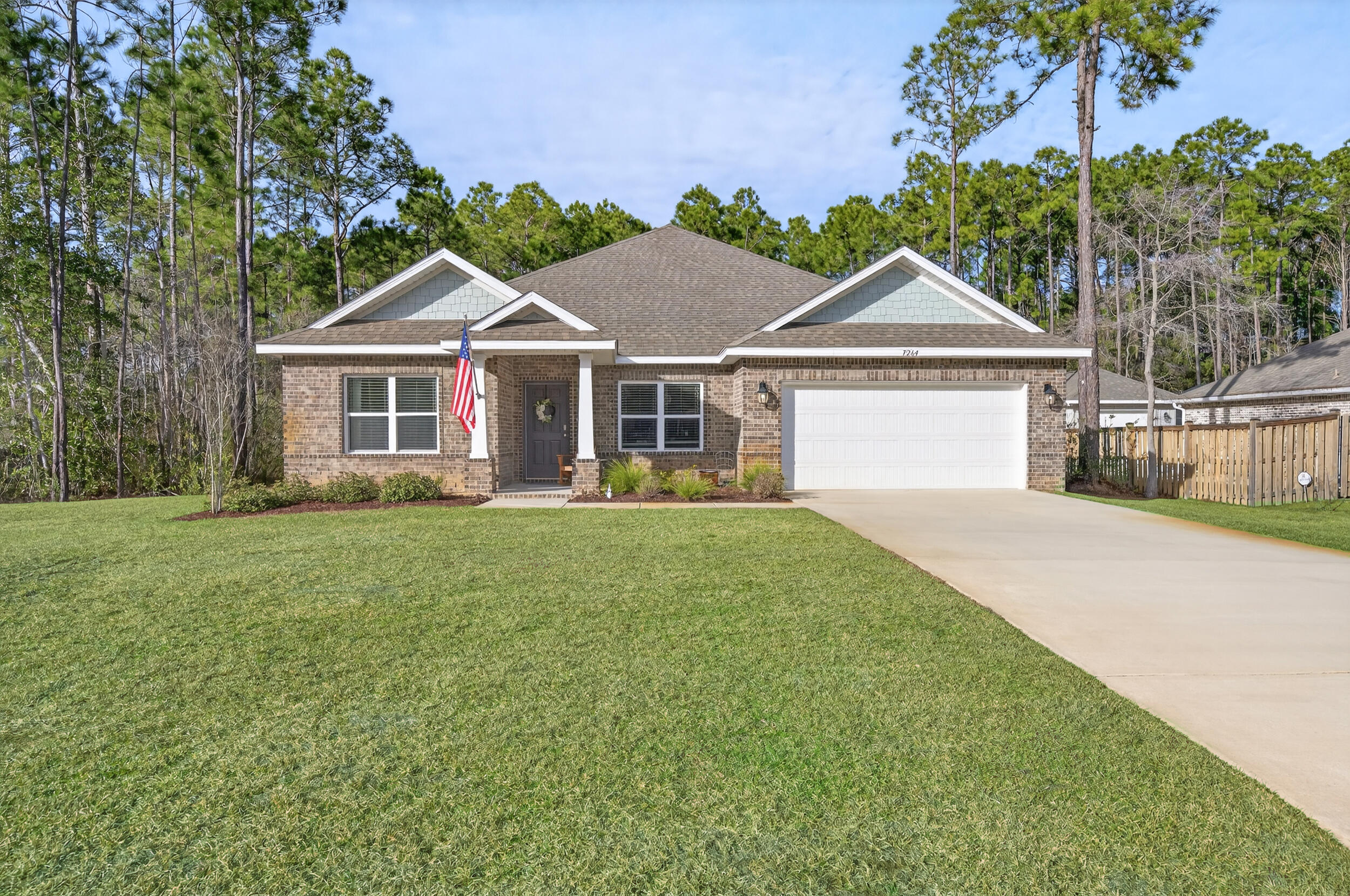 Built in 2023, this stunning Carlton B floor plan by Holiday Builders is located in the heart of Holley By The Sea and offers the perfect blend of modern design, privacy, and comfort. Set on a quiet street with underground utilities and no overhead power lines, the home sits on a spacious half-acre, tree-lined lot with exceptional curb appeal. This thoughtfully designed home offers 3 bedrooms, 3 full bathrooms, and a designated office space. Inside, you'll find a bright and airy open concept layout featuring high ceilings, recessed lighting, and a neutral color palette throughout. Luxury vinyl plank flooring flows through the main living areas, with carpeted bedrooms for added comfort. The expansive living room seamlessly opens to the kitchen, creating an ideal space for both everyday li ving and entertaining. The kitchen features a large island, granite countertops, white shaker style cabinetry, a gas range, stainless steel appliances, a Samsung Bespoke refrigerator (with stainless steel panels available), and a pantry. The primary suite features a trey ceiling and an en suite bath with a double vanity topped with granite countertops, a large tiled walk-in shower with glass panel, a water closet, and an exceptionally spacious walk-in closet. Secondary bedrooms are positioned on opposite ends of the home, including one tucked into its own private hallway with the ability to close off the space entirely. Out back, enjoy a serene setting surrounded by mature pine trees. The truss-covered 16'10" x 7'6" porch is the perfect place to relax! The yard is equipped with a sprinkler system and shallow well. This beautiful, move-in-ready home offers modern living in one of Navarre's most desirable neighborhoods. Holley By the Sea offers exceptional amenities, including an outdoor pool and an indoor lap pool, a fitness center, tennis and basketball courts, a boat ramp and pier, a soundside beach area, sauna, and more. (See MLS docs for full list of HBTS amenities).