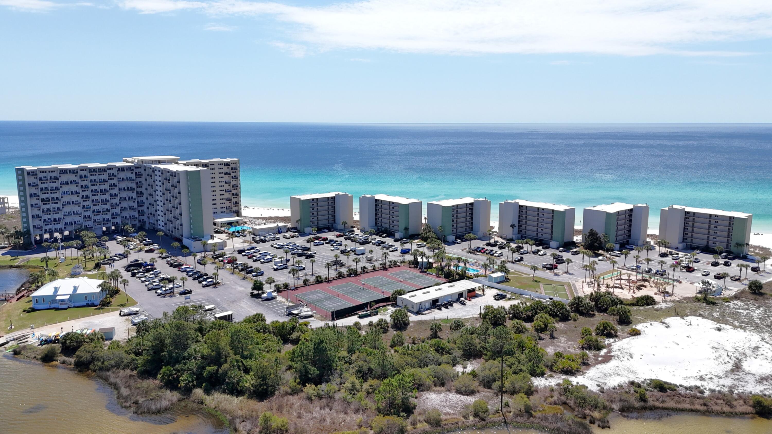 Truly a one-of-a-kind location! There's something different about Pinnacle Port. Built in 1977, this timeless resort carries the soul of Old Florida, a slower, sweeter era when a beach vacation meant barefoot mornings hunting for seashells, lazy afternoons on the shuffleboard court, casting a line off the dock at dusk, and gathering with neighbors for a sunset picnic on the lawn. That unhurried way of life didn't disappear here, it was preserved and is waiting for you to discover it.
Pinnacle Port occupies one of the most extraordinary and naturally protected parcels on the entire Gulf Coast. To the west lies Camp Helen State Park, a pristine, largely undeveloped stretch of protected coastline that ensures your views and your peace will never be crowded out by development. To the north,  the shimmering expanse of Lake Powell, the largest coastal dune lake in North America and a designated "Pristine Florida Waterway" provides a breathtaking backdrop of calm, emerald water. To the south, the Gulf stretches endlessly, just steps from your door. Access is through the charming, tree-lined streets of Carillon Beach, which ensures your privacy.
This rare geography means Pinnacle Port is surrounded on all sides by natural beauty and protected land, making it one of the few remaining places on the Gulf Coast where you can look in any direction and see nothing but water, dunes, and sky. It is quite simply, irreplaceable. 
Unit 607 in Building B2 delivers the kind of unobstructed, sixth-floor Gulf front views that make every morning feel like a vacation. Step inside and you're immediately greeted by a bright, open living area dressed in warm hardwood style flooring and coastal charm. The living room with sliding glass doors that frame a stunning live picture of the Gulf, opens directly onto your private balcony. The bedroom is equally impressive, with its own large Gulf-facing window that fills the room with natural light and that same dazzling blue-green water view. This unit makes a great vacation rental, or is also suitable for year-round living.  Schedule your showing today!