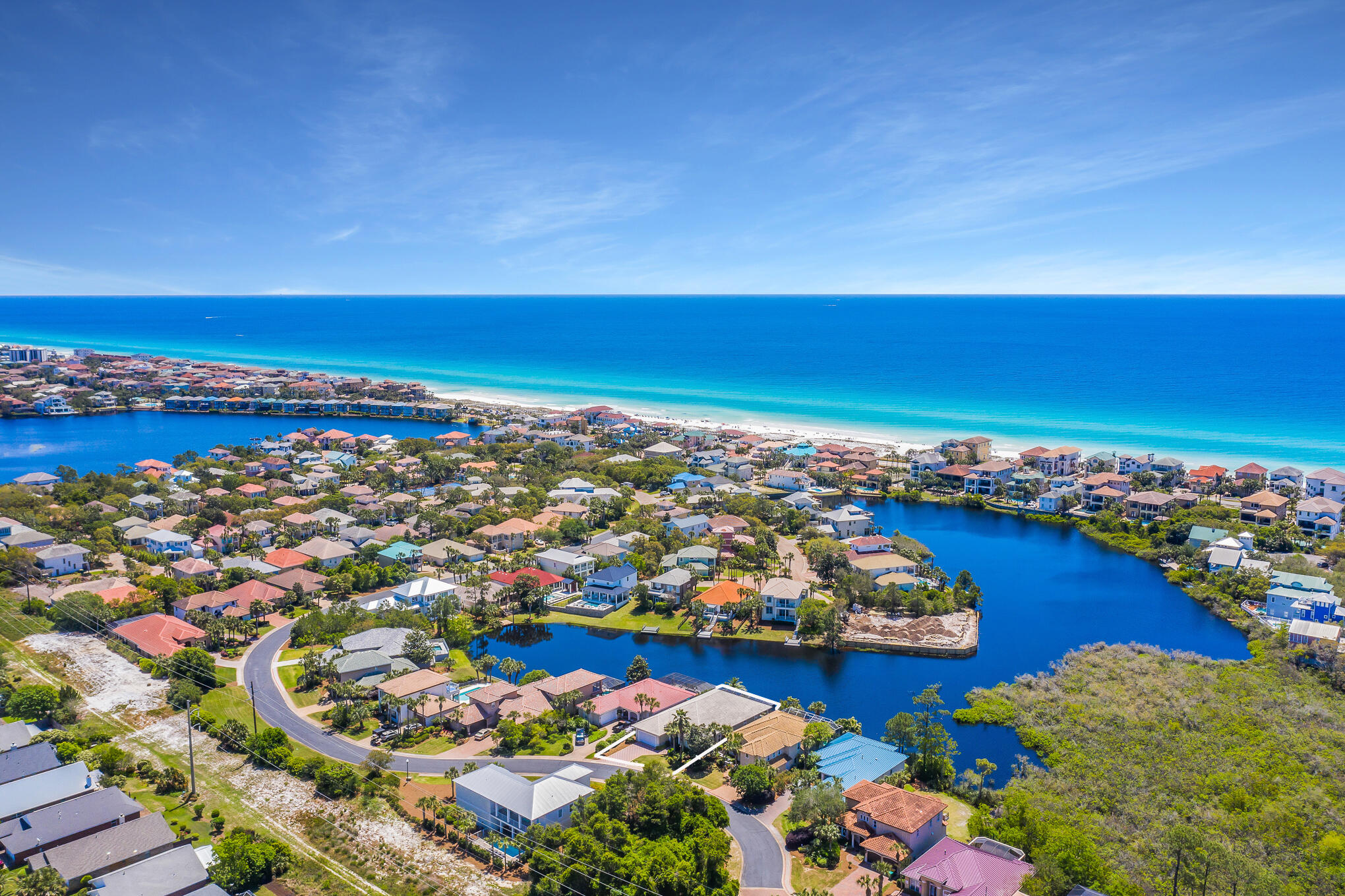 Prominent lake front positioning paired with an expansive single level floorplan solidifies this charming beachside villa perfectly poised within the gated enclave of Destiny S/D. Notable features include three sizable bedroom suites with an additional fourth media / potential bedroom space as well as impressive 12' ceilings throughout the home yielding an open floor-plan that takes full advantage of the south facing lake frontage. The central living area is comprised of a fabulous chef's kitchen which offers finely appointed finishes including custom cabinetry, professional appliances and is open to the dining area, living room with fireplace and wet bar as well as direct access to the lakefront screened lanai. The master suite is separate from the main living areas and offers direct access to the back patio and private pool as well as two closet spaces and an ensuite bathroom offering dual vanities, a soaking tub and a walk in shower. Other notable features include an air conditioned oversized two car garage as well as multiple covered + screened porches on the front and rear elevations. Each bedroom suite offers it's own ensuite bathroom for optimal convenience. This home has been meticulously maintained; it conveys turn key and ready for immediate occupancy with a centralized location in Destin, FL adjacent from beautiful beach access, world class shopping, dining and local entertainment.