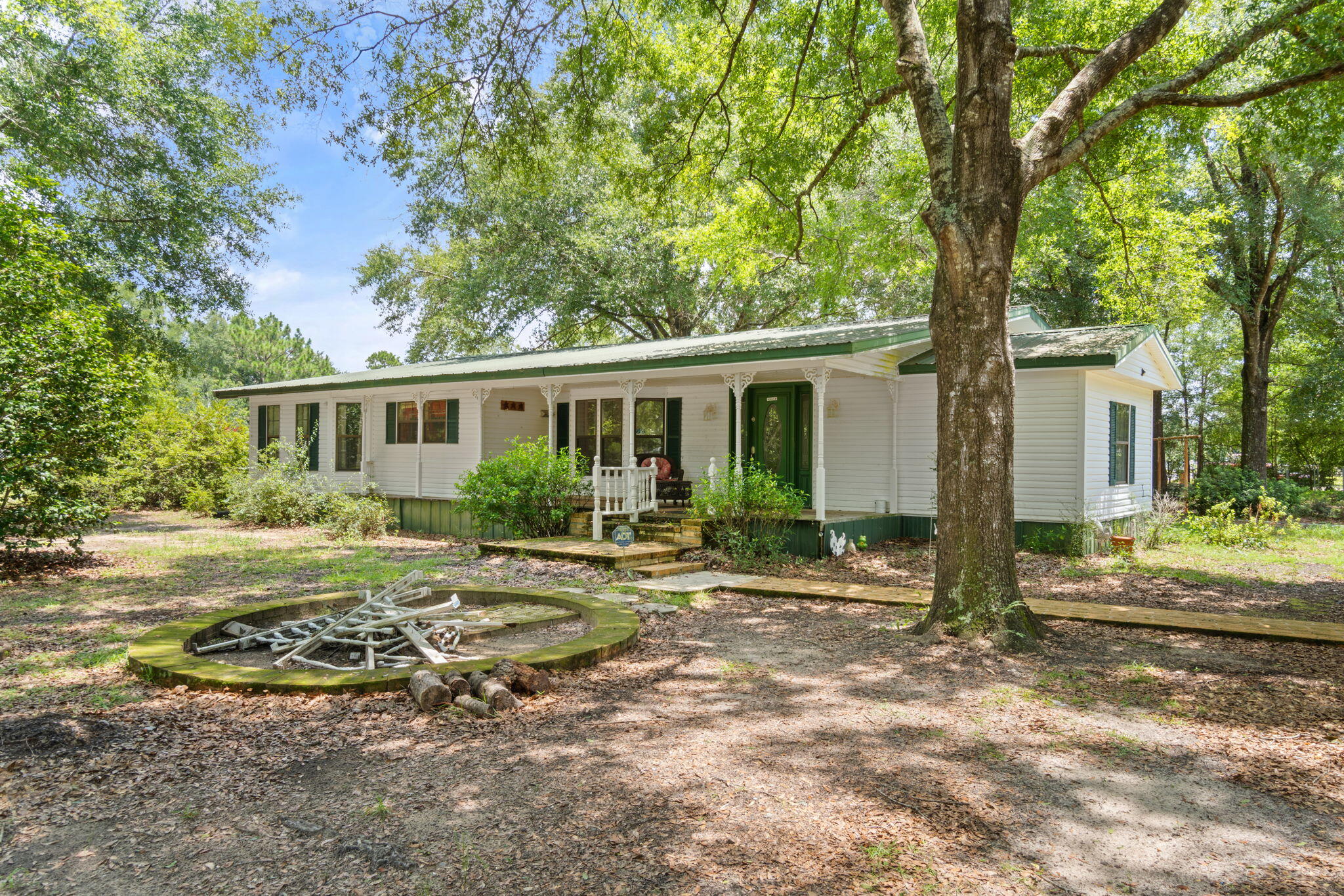 No HOA! Welcome to this spacious 3-bedroom, 2-bathroom home, offering 2,184 square feet of living space on nearly 1 acre just outside of Crestview. Set beneath a stunning canopy of oak and mature trees, this property provides a blend of privacy and natural beauty. The home features a metal roof, HVAC system updated in 2020, and a water heater replaced in 2018, ensuring comfort and durability. Manufactured home with a large addition to be sold ''as-is.'' Additional features include an oversized 2-car carport on a concrete pad and a new 12x16 metal shed with double doors, also situated on a concrete pad. Enjoy the convenience and possibilities on a level & dry lot with ample parking. Located less than an hour from the Beaches, Destin, Pensacola, Blackwater St Park, just a short drive to I-1