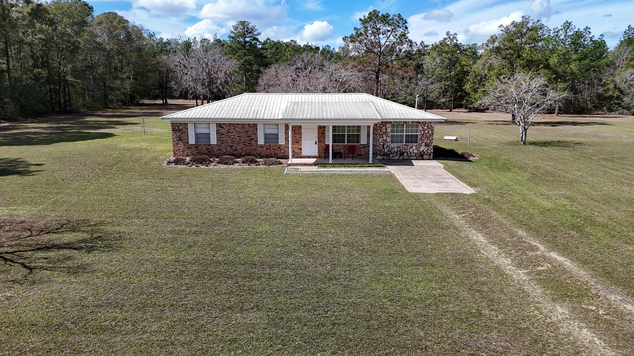 Here's a home that checks all the right boxes. Sitting on nearly 17 acres of level land including approx 5 acres of timber, this well-maintained 3 bedroom, 1 bath gem comes ready to enjoy. The metal roof was updated in 2012, a brand new heating and cooling system installed 2024, and fresh laminate flooring in most rooms. You'll love spacious kitchen/dining combo with pantry, expansive living area and a sunroom that isn't included in the square footage.  There are also four sheds for all your storage needs. With easy access to town and beaches on paved road frontage, this kind of acreage at this price point just doesn't come around often. Don't let this one slip away. Contact your favorite agent today. Also includes Parcel ID:  21-2N-18-09000-004-0020.