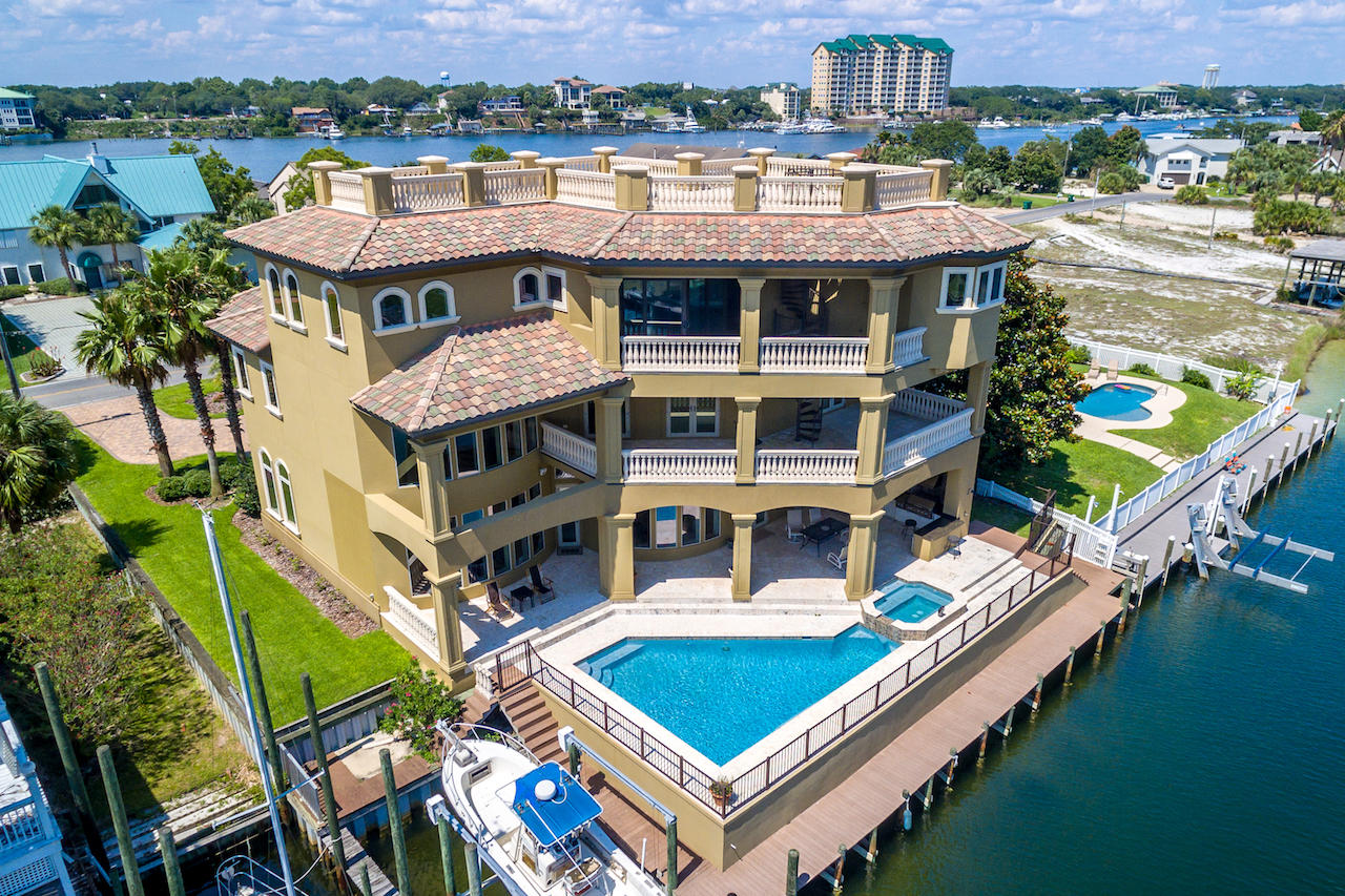 This custom-built, canal-front beauty is the perfect place to store your boat and enjoy the perks of living on the water in the heart of Destin. Watch the fireworks from multiple balconies and enjoy the 75ft dock and boatlift that accommodates up to a 30ft boat. The fabulous heated salt-water pool, hot tub and outdoor living area, complete with built-in grill and coral stone pavers, complement the outdoor lifestyle. As you walk through the custom wood doors, you are greeted by a double row of curved, canal-front windows extending the height of the 22ft ceiling. Imported Marbella shell stone adorns the floors, while painted coffered ceilings add architectural interest. The dramatic gas fireplace encased by built-in cabinetry and beautiful surround extending to the ceiling is a focal point. With cherry cabinets, beautiful granite counters and high-end appliances including a Wolf 6-burner range with double ovens, Bosch dishwasher, Fisher Paykel dishwasher drawer, wine cooler and Viking stainless refrigerator, large walk-in pantry, breakfast bar, and dining area, the chef's kitchen will delight the epicurean in your family. Also on the first floor, there is a formal dining room, a game room, a half bath and a laundry room with cabinets, a laundry shoot and an extra refrigerator. The beautiful curved stairway with iron railing leads to the second floor with three guest suites. There is also an office or den on this level. You will also enjoy Gulf views from the large second floor balconies. The third floor boasts a large master bedroom with sweeping views of the harbor and Gulf. The large master bath includes a jetted tub, large walk-through shower with double showerheads, and double vanities with unique Rainforest Brown granite. There are his and hers walk-in closets with custom cabinets and shelving. A morning coffee bar complete with a sink and refrigerator allows easy access for that first cup of coffee to be enjoyed on the balcony.  Also on this level are other rooms that could be used for a hobby room, exercise room, office and bedrooms. The spiral staircase on the balcony leads to a rooftop deck with amazing views of the harbor, Gulf and East Pass. Additional custom features include an elevator, smart house wiring, Brazilian cherry hardwood floors on the second and third floors, faux finishes, generator wiring, three AC units and vessel sinks. The first level of the home is concrete block up to 12' and was built on 90 pilings. Take your boat to Crab Island, the Harbor or the Gulf and enjoy waterfront living at its finest.