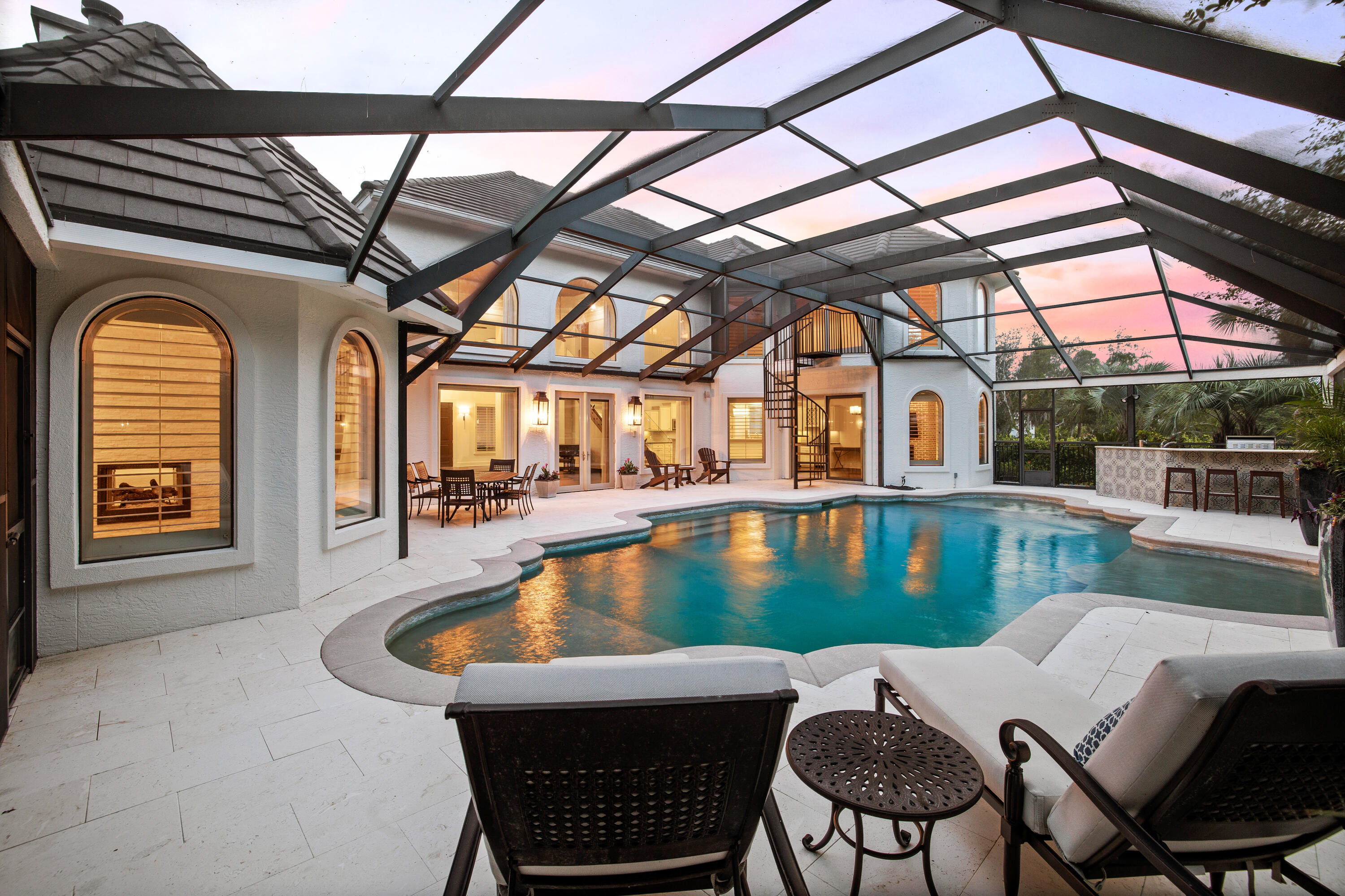 Tucked inside of the gated community of Regatta Bay sits this renovated waterfront Spanish-style estate. This stunning residence is perfectly positioned on the lake and just a short stroll from the bay. Upon entry, you are greeted by the spacious living room with 22' ceilings, a beautiful brick fireplace, and floor-to-ceiling windows flooding the room with natural light. the open floor plan allows for seamless entertaining and connects the living room to the kitchen and dining area. The chef's kitchen features dual ovens, a gas stove, oversized island, dual sinks, and a wet bar with an ice maker and wine cooler. The dining room showcases a brick fireplace and views of the stunning outdoor living area. The master bedroom boasts a two-sided fireplace with a sizable seating area overlooking the pool. The updated master bathroom features dual sinks, a free standing tub, a private water closet, and oversized shower with dual shower heads. Additionally on the first level is a flexible space with a fireplace and built-in cabinetry. A half-bathroom, laundry room, elevator access, and two-car garage complete the first level. 

The modern wood staircase leads you to the second level which features the remaining bedrooms. Two of the bedrooms are connected by a Jack-and-Jill bathroom with a soaking tub. The second-level flex space is oversized and flooded with natural light. This large room provides stunning views of the lake and features sliding glass doors that allow you to access a spiral staircase that descend to the outdoor living area. An additional bedroom, full bathroom, wet bar, and elevator access complete the second level. 

The luxury outdoor living area is configured around the stunning, oversized pool. This space is covered by a glass enclosure, allowing for outdoor enjoyment no matter what the weather is. Designed with entertaining in mind, the outdoor space features the large pool, plenty of seating for lounging and dining, and a luxury outdoor kitchen with tiled bar, all while being surrounded by privacy landscaping and the lake as the backyard. 

The sought-after neighborhood of Regatta Bay provides homeowners access to their renowned golf course and academy, a community pool and clubhouse, the Rubio Tennis Facility, the Yacht Club Pool overlooking the Bay, and much more. 347 Captains Circle is perfectly positioned minutes from sugar sand beaches and turquoise waters, world-class restaurants, shopping, entertainment, and champion golf courses.  Inquire today to schedule a private showing and start living the coastal lifestyle you deserve!