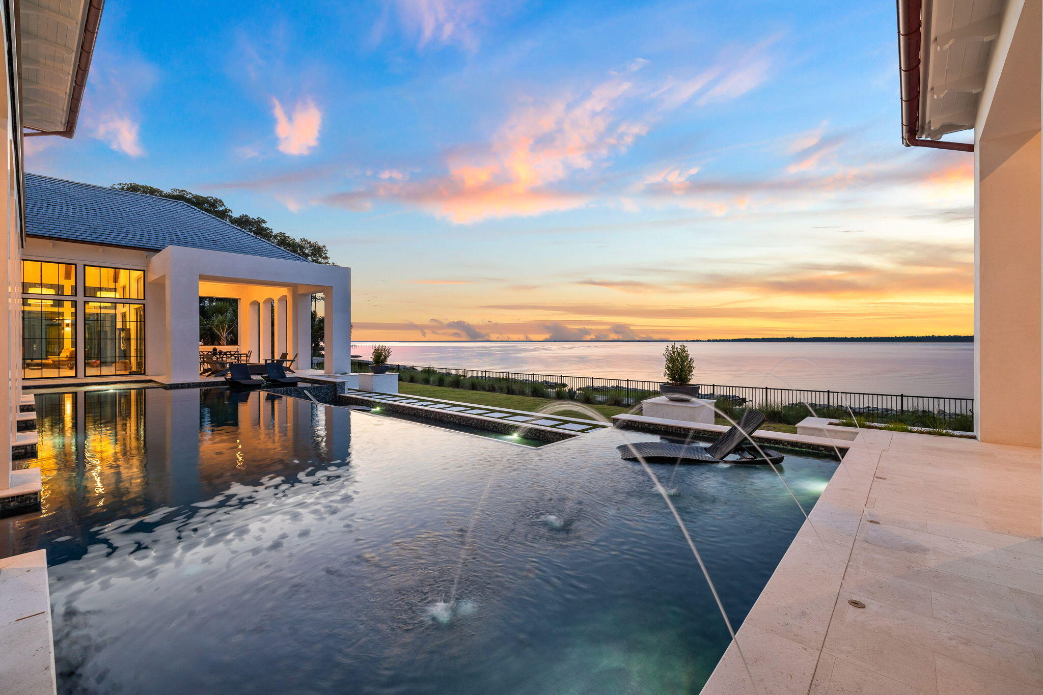 Primely positioned on an irreplaceable double homesite spanning an impressive 150'+ along the historic Choctawhatchee Bay, 51 Junop Court is an extraordinary Legacy residence nestled within the prestigious gated enclave of Churchill Oaks. Iconic architectural design by renowned architect Matt Savois juxtaposed masterful construction quality characterize this all-concrete home built by Grand Bay Construction with notable features including six spacious bedroom suites, seven custom bathrooms, and meticulously designed 7,587 sqft of highly curated living space by Erika Powell at Urban Grace Design. Unique even within Churchill Oaks, this exceptional residence proudly presents a 4-car garage with private parking court, a coveted amenity perfect for car enthusiasts or those seeking ample storage. This property also yields access to a 70'+ private boat slip, one of the only large slips with immediate adjacency and excellent proximity to the white sand beaches of 30A.

Gracing the pristine bayfront, this home stands as a testament to coastal modern architectural trends with its all-concrete construction, exuding both strength and contemporary allure. The open living floorplan is beautifully accentuated by floor to ceiling steel and glass aesthetic windows that immediately draw attention to the resort style amenities and pristine water views of the northern elevation. Notable interior features include a 10' custom chevron solid core entry door, 12'-20'+ ceiling heights across the first level, ample entertaining space including indoor and outdoor formal and casual living. The private and oversized primary suite directly facing the water is comfortably situated on the east wing of the first floor, offering a haven of tranquility and luxury complete with a separate laundry room, spa-like ensuite bathroom, dual closets, private porch with fireplace and expansive water views.

As you explore, discover the open and inviting vaulted kitchen and living areas adorned with elegant beams, creating a captivating ambiance of grandeur and comfort. The first floor boasts a pass-through bar seamlessly connecting the interior to the pool area, offering a perfect blend of indoor-outdoor living, ideal for entertaining guests or enjoying tranquil moments by the poolside.

The resort style amenities include a sizable private pool area yielding to a stylistic infinity edge with functional tanning and lounge basin as well as an adjoining spa, swim up bar and private covered porch space.

Venturing upstairs reveals a haven of relaxation and additional privacy, hosting the remaining bedrooms, each accompanied by it's own ensuite bathroom with direct bay views, a luxurious touch that ensures unparalleled comfort for all residents and guests. Additionally, a recreational area and office space provide versatile options for leisure and work within the confines of this exquisite estate.
Adding to its allure, the property features handcrafted Moroccan tiles, lending an artistic and unique character to select areas, complementing the home's luxurious ambiance.

Notably offering a 70' deep-water boat slipthe only one of its kind near 30Aa 50' infinity-edge pool with a swim-up bar, and awe-inspiring bay views, 51 Junop Court caters to the desires of boating enthusiasts and connoisseurs of luxurious coastal living.

This residence is more than just a home; it's an embodiment of coastal sophistication, seamlessly blending modern comforts, architectural innovation, and breathtaking vistas to create an unparalleled living experience along the coveted 30A coastline.

Please reach out to us today for the cost-to-own figures for this property.