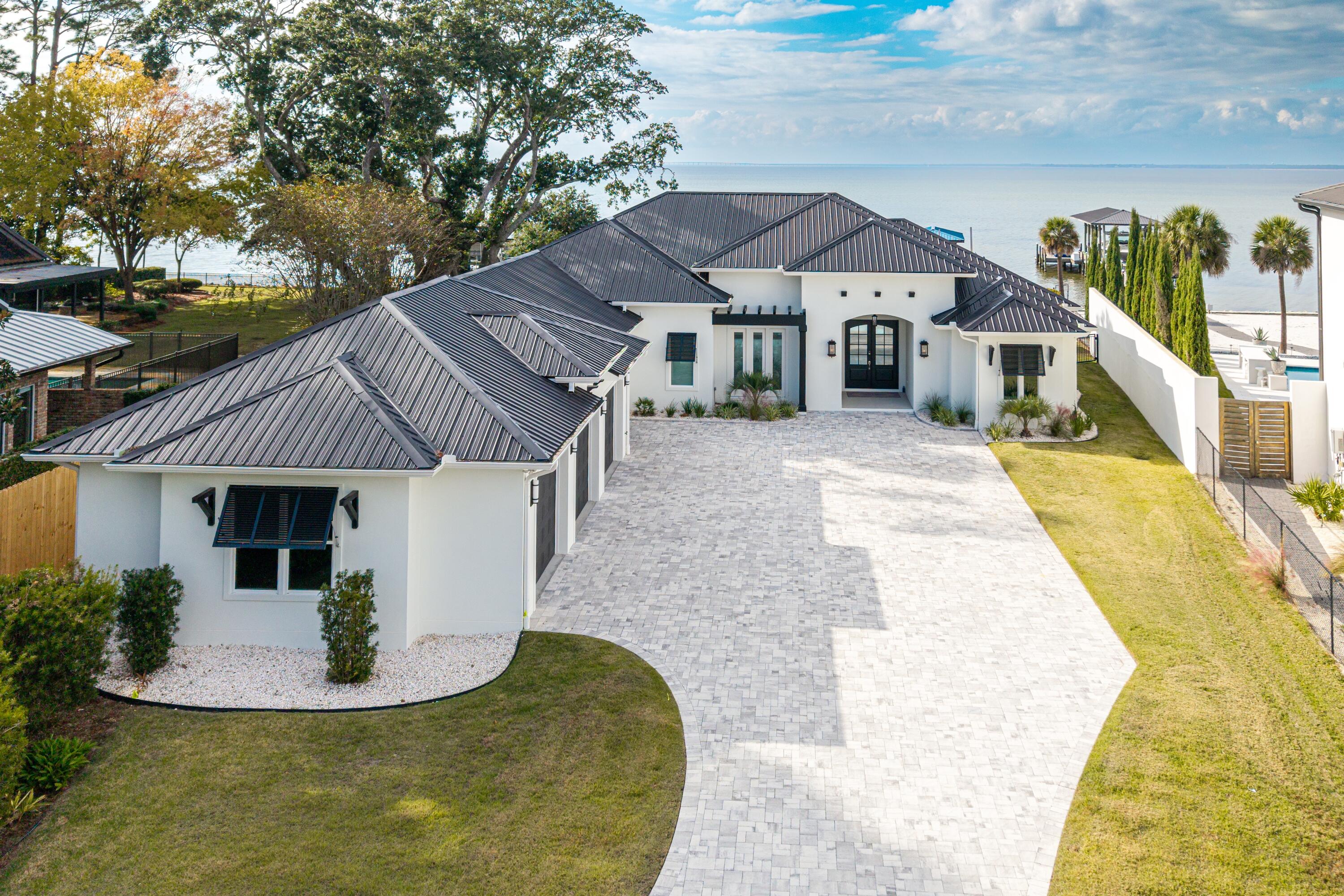 ***$100,000 Buyer Bonus for closing costs, furniture, or anyway you chose!*** Experience unparalleled bayfront living in this 2022 custom-built estate, positioned on nearly one acre behind a private gated entrance. Designed entirely on one level with 10ft ceilings, this residence blends luxury with efficiency—featuring a rare 1,525 sq.ft. 4-car garage and a complete home solar system with bi-directional metering for low electric bills. Perfectly oriented to capture breathtaking sunsets over the western sky, this home offers resort-style outdoor living with a heated saltwater pool and spa, 800 sq.ft. covered lanai with full summer kitchen and Green Egg smoker, and 117 feet of pristine bay frontage complete with dock, swim platform, and boathouse accommodating up to a 30' vessel. Peace of mind comes standard with impact-rated storm windows and doors, metal roof and a whole-home generator. 
Inside, every finish has been carefully curated with whitewashed hardwood floors, quartz countertops, dual living spaces with a two-way gas fireplace, remote electric blinds, and Bluetooth fans. The entertainer's kitchen boasts a double oven gas range, expansive center island, large walk-in pantry, and bayfront dining nook with built-in seating.

The waterfront primary retreat offers its own private covered porch and a spa-worthy ensuite with dual vanities, walk-in shower, soaking tub, and dual walk-in closets.

Sunset serenity, luxury craftsmanship, and energy-efficient living - all in one extraordinary bayfront estate.

Enjoy a community park equipped with a playground, tennis courts, picnic tables and more. Driftwood Estates is conveniently located near Sacred Heart Hospital, Publix, fabulous dining and shopping in Grand Blvd, and just a short drive to the beaches of 30A.