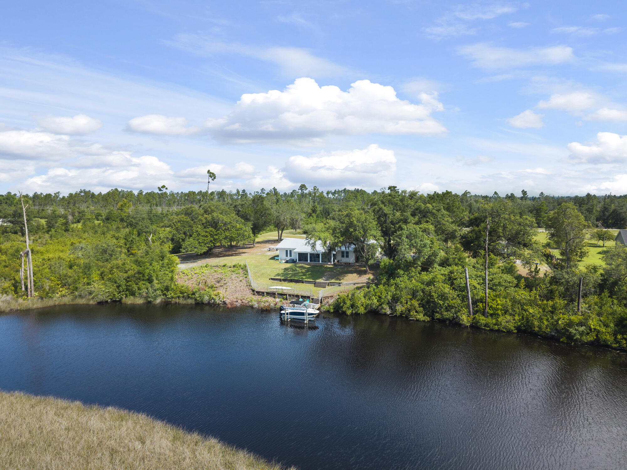 Rare opportunity to own a beautifully updated 3-bedroom, 2-bath brick home with Gulf access, situated on 5 private acres along Cook's Bayou. This property offers exceptional flexibility—bring the boat, RV, four-wheeler, or horse—with room to live, work, and play in a peaceful waterfront setting.

Built in 1976 and thoughtfully renovated, the 1,855 sq ft home blends classic character with modern upgrades. Interior features include fresh paint, quartz countertops, new ceiling fans, and closet organizers throughout. The primary bathroom has been fully remodeled, and the kitchen is equipped with an induction cooktop, double ovens with convection and air-fryer modes, and stainless steel appliances—all less than three years old. Significant improvements include popcorn ceiling removal, 2024 HVAC, Honeywell programmable thermostat, Pristine Air UV filtration system, water softener, generator outlet, 2017 metal roof, hurricane ties for wind mitigation, and a whitewashed brick exterior.

Outdoor amenities include a solar-powered gated entrance, 12'x32' shed, motorized screened back porch, raised metal garden beds, citrus trees, private pond, and mature moss-draped oak trees. Nearly $30,000 in dock upgrades include an expanded dock and 7,000-lb boat lift, providing direct access to the Gulf.

Property sits on tidal waters with Gulf access through Cook's Bayou. Bridge vertical clearance is approximately 9'6", suitable for smaller boats. John Deere tractor and attachments convey with sale.

Ideal for a private waterfront homestead, recreational retreat, or future expansionthis unique property offers space, privacy, and true Florida waterfront living.