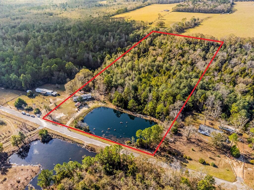 Come build your secluded dream home on this quiet, dead end street in North Milton. On this almost 10 acre lot you'll find a 2 acre stocked pond and a creek running through the back of the property. Improvements on the property include a private well, septic tank and electricity. Water is available and ready for hook up. A well maintained manufactured home sits on the property, where you can live while building your dream home. Enjoy quiet mornings sitting on your front porch swing and beautiful pond view.  Just 10 minutes to Jay and 24 minutes to Downtown Milton shopping and dining. Only 15 minutes to Whiting Field. Located less than 1 hour from Downtown Pensacola and Pensacola Beach.