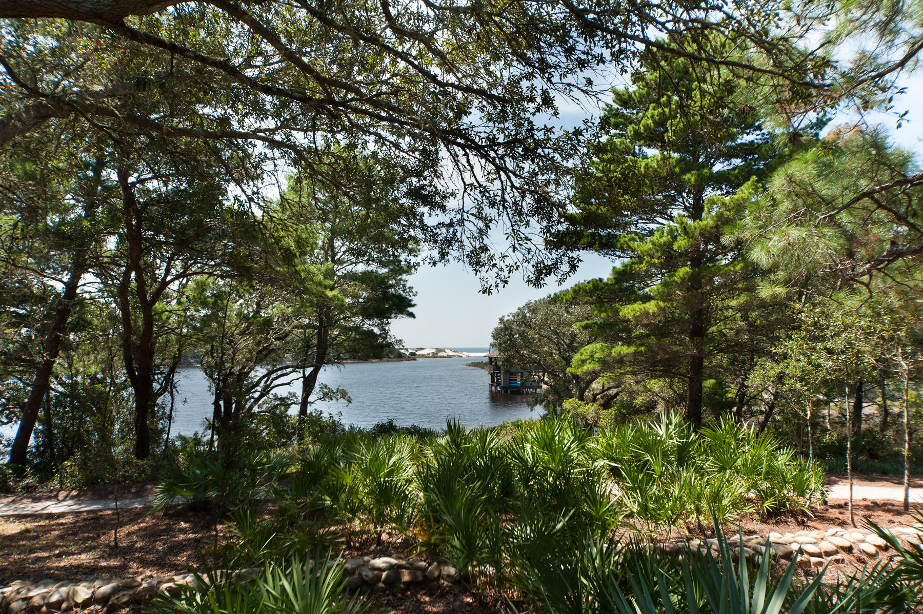 Located in the east peninsula of Draper Lake Coastal Village, this lakefront property sits adjacent to a scenic path tracing the shoreline of Draper Lake on its way to one of two community docks situated directly on the south side of the lot. With only one immediate neighbor, and buffered by the green area to the west, it offers exceptional privacy. Set so close to the dock, neighborhood amenities on either gated peninsula are within easy reach. Closest is one of two pools whose pavilions with outdoor fireplaces are appointed with comfortable, high quality outdoor furniture. With the carriage house complete, this property has home plans by architect T S Adams Studio Architects, Inc. including a 3,840 square foot main house with a spa situated between it and the carriage house which is 647 square feet. 

Over the bridge is the 40-foot observation tower capturing panoramic views that include the Gulf of Mexico. Owners may keep their paddle boards at one of two boat houses on Draper Lake, providing access to its placid brackish waters. Adventure to the outflow of the lake which occasionally breaches the white sand beach to meet the gulf. Just over a quarter mile down a neighborhood street is a private rest facility with golf cart parking, reserved exclusively for Draper Lake owners, just yards away from beach access.