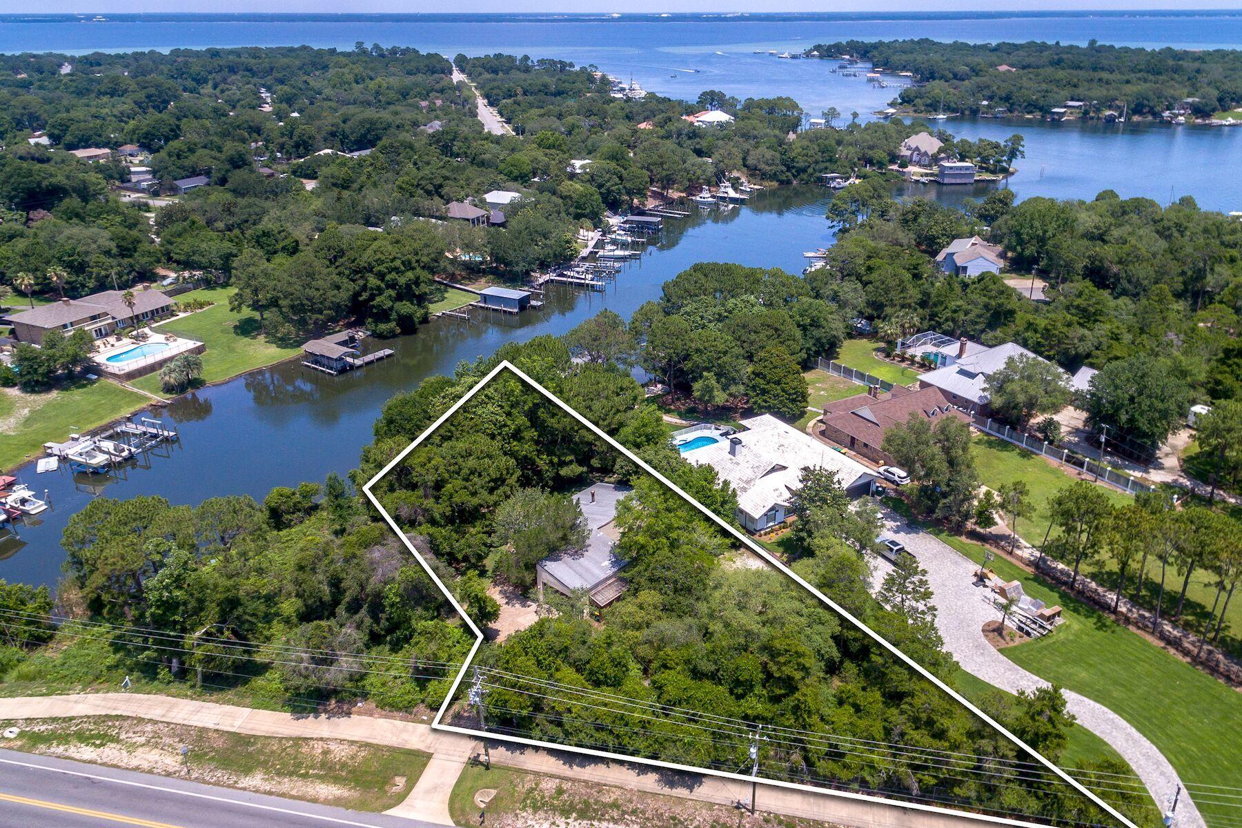 If nestled in the woods on deep water with a dock sounds appealing, then this is a wonderful opportunity to claim your Florida dream lifestyle. Mature trees shade the front and back of the property with the house at its heart. Your own private boardwalk leads to the dock, which is suitable for mooring a vessel and cruising the entire 30-mile long Choctawhatchee Bay starting from your own backyard. The 114 feet of waterfront is nicely mulched under the trees with two wood decks for patio furniture. Add a fire pit and grill, and you can experience outdoor living in a very special, private sanctuary. The stucco exterior and single floor living spell convenience and low maintenance. There are two bedrooms, two bathrooms and an attached 2-car garage and workshop space. A large living room sports a wood burning fireplace, built-in shelves and large windows for natural daylight filling the room. Here is an opportunity to bring all you have seen and learned on those home improvement shows and transform this home into the one you have always wanted - your colors, your style, your fixtures, your decor. It is a little hidden gem awaiting its new owners.