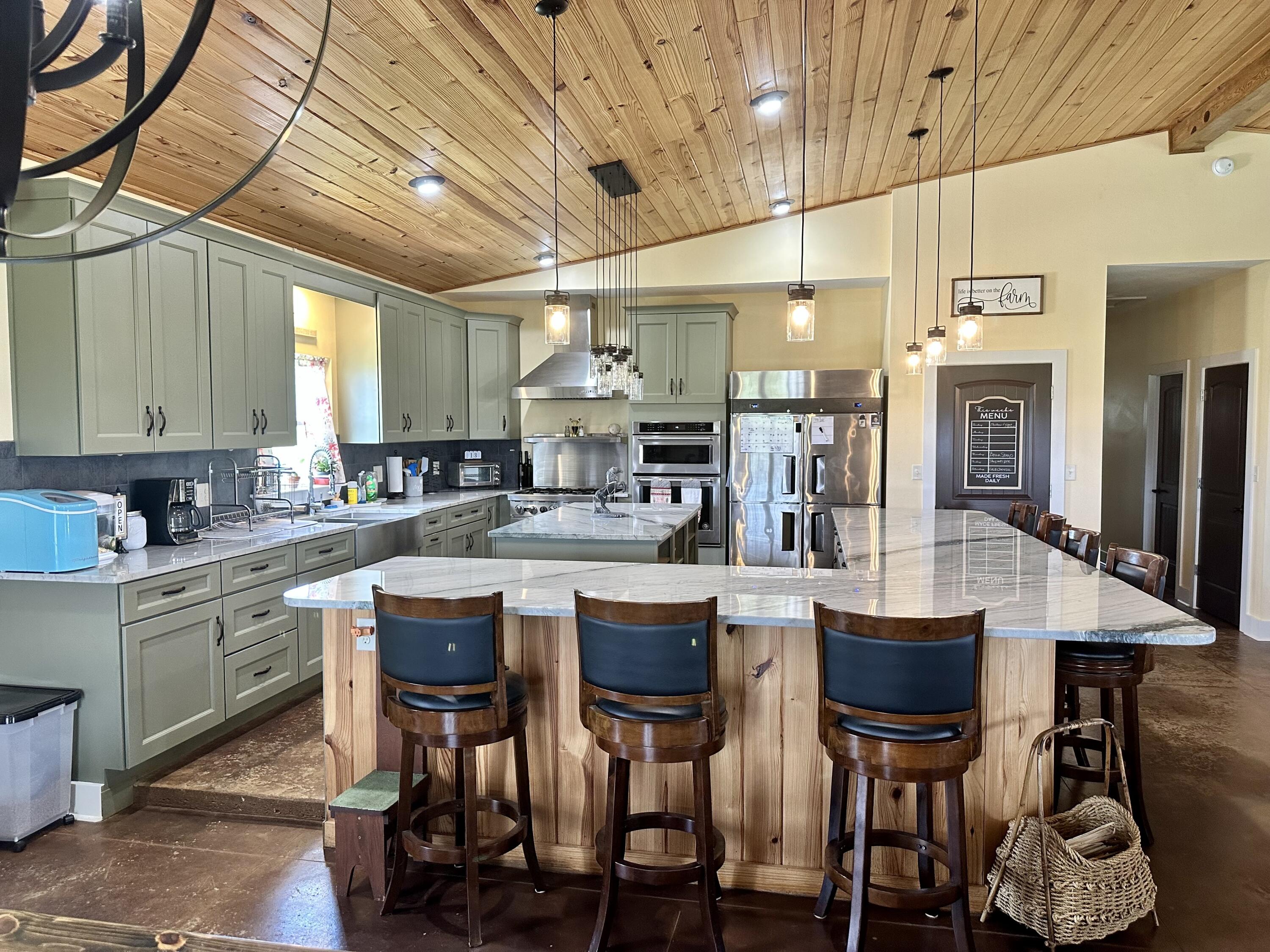 The possibilities are endless in this craftsman style custom farmhouse that offers a unique blend of distressed rural charm and contemporary flair while providing you with timeless character set amongst an impressive 10 acres. With its traditional focus on nature, you'll enjoy the many attributes that make this home a rarity including a sense of peacefulness, privacy, and enjoying room to expand. You'll find tranquility watching the Florida sunsets and soaking in the crisp air amid an extensive front porch flanked by ceiling fans and tapered columns overlooking the sprawling green lawn. From the moment of entry, you are captivated by an expansive open floorplan that has perfectly combined farmhouse chic with a simplistic approach with its maintenance free stained concrete flooring, peaked wood tongue and groove ceiling, and attractive exposed wood beam leading to the massive industrial fan and fixtures throughout. The main living space is truly a dream come true for any entertaining enthusiast with a its broad openness and light-filled living space containing bountiful windows and recessed lighting. Cooking for the masses has never been easier in the remarkably well-equipped kitchen that serves as the primary location for more intimate gatherings. The immense kitchen presents all commercial grade stainless steel appliances, large island with chic shelving, massive wrap around hop up breakfast bar, oversized stainless farmhouse sink, canning jar lighting, sizable pantry, and cheerful color palette consisting of neutral granite with stylish olive cabinetry. The appliances consist of a 4-door freezer/refrigerator, a six-burner gas stove top, stainless range hood, and three ovens. Through the hallway, you are led to the owner's suite, guest bedroom, and laundry. The owners' quarters consist of a generous space for large bedroom furniture or seating area as well as two trendy barndoors leading to master bath and walk-in closet with custom pipe shelving. The spa-like master suite features an oversized granite vanity and large tiled walk-in shower. The secondary room has great closet space, ceiling fan, and easy access to full bath located in hall that entails a granite vanity and shower/tub combo with tiled surround. At the rear of home, there is a separate oversized laundry room with built-in coordinating cabinetry that could also serve as additional storage space. Outside, this home is even more amazing, consisting of an array of features that adds to this home qualities. You'll find two split AC units, a generator, and an oversized carport for parking owners vehicles or equipment (Pole Barn). This home offers you the feeling of getting away from it all, yet still reasonable distance to commuter routes while having your own private oasis on the 10.28 acres of cleared land!! Call today for a private showing.
