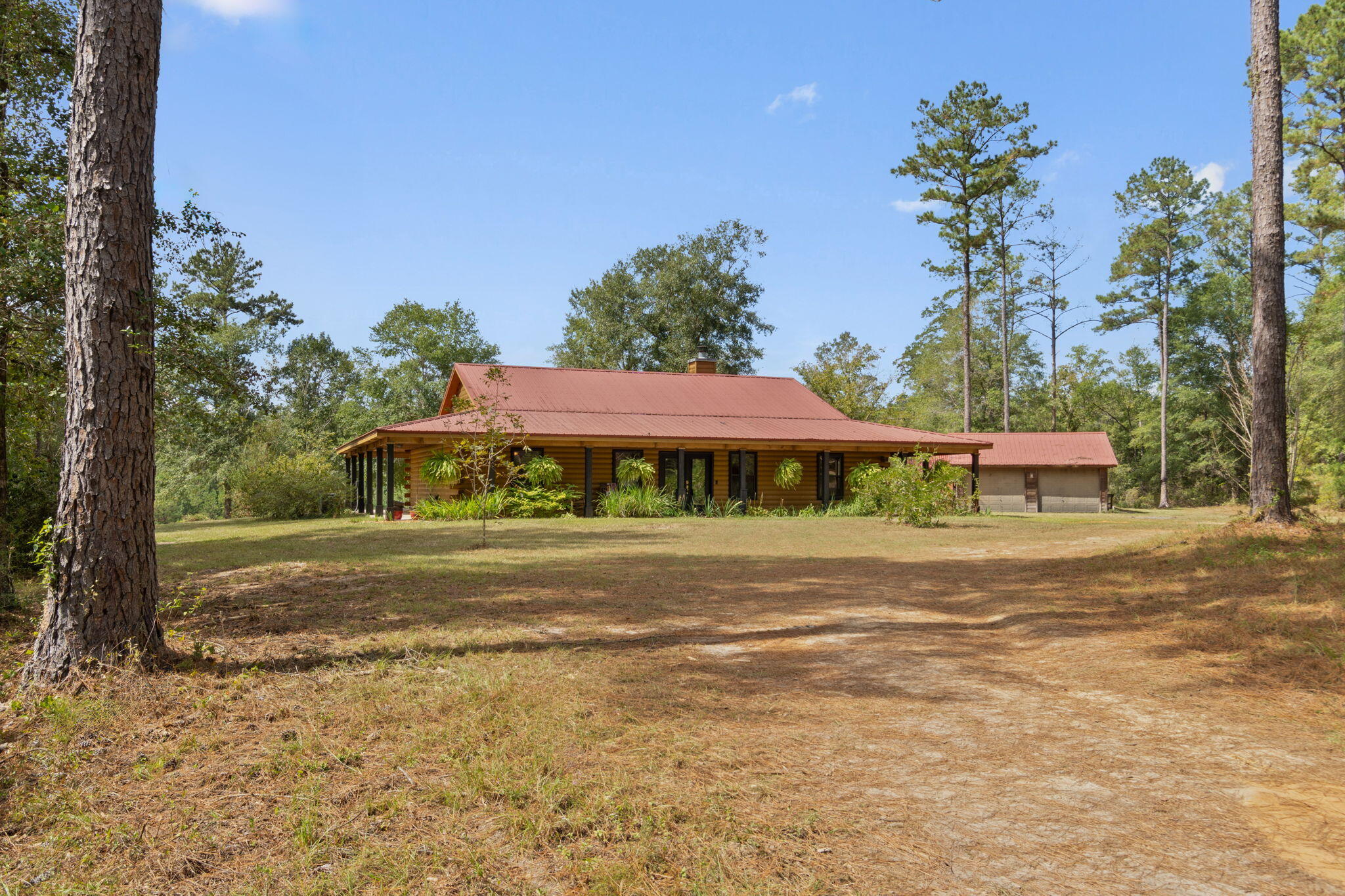Slice of Paradise in North Florida!!! If you're looking for that country home and plenty of room to roam, then look no further! Charming log cabin home on 260 +/- acres with a lake and a clear sandy bottom creek running across the property. Home is tastefully appointed with plenty of wood work - modern kitchen with granite tops - expansive living and dining areas with vaulted ceilings - split bedroom design and a wonderful porch for enjoying the fabulous views. Additional features include a large metal barn - 2 stall horse barn with tack room - garage/workshop and lean to for the tractor and toys -  and a ready made arbor. Wildlife galore on over 260 acres that features a mix of mature and various age pines as well as hardwoods. Roads/trails running throughout the parcels. Plenty of possibilities to put your personal touch on this slice of paradise in beautiful Laurel Hill, Florida!