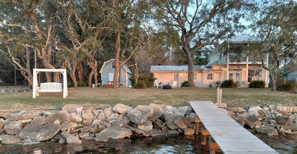 Exquisite waterfront home located on 1 acre on East Bay features quintessential Florida landscaping. Savor the tranquil setting while watching dolphins frolic in the Bay or viewing the Blue Angels practice their daring maneuvers. Open floor plan, 3 bedroom 2. bath home showcases LVP and tile flooring downstairs, new cabinets, and gorgeous granite counters. The generous upstairs master suite facing the water includes a balcony and en-suite bathroom. Outside, take note of a sprawling lawn with a 52' dock. The covered patios, dock, yard swings, lighted grill area and numerous backyard seating offer plenty of entertaining options right on the Bay. Water views abound from almost every angle in this beautiful home. There is a separate yard building and dog area.   Currently being used as Airbnb.