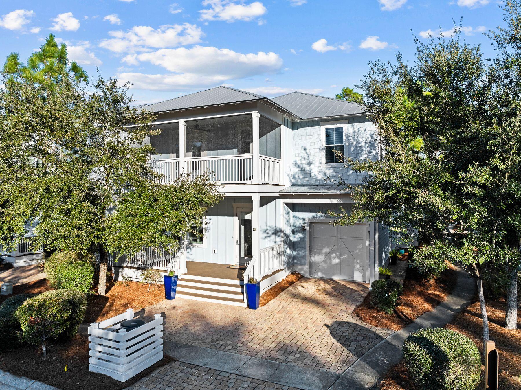 Why choose between nature and beach, when this well-appointed Florida cottage offers both? Located near the entrance to the highly desirable NatureWalk neighborhood, this splendid home is just a mile from the beach along a scenic walking trail. The brick driveway leads to a one-car garage and welcoming front porch. Built in classical style, the entrance foyer opens to a formal dining room, boasting a noteworthy coffered ceiling and wainscot walls. The adjoining walk-through butler's pantry includes a wet bar with a built-in wine refrigerator, making this room perfect for entertaining. Solid hardwood flooring continues past a laundry room (one of two) and a powder room to the open great room. The chef's kitchen is oversized with a Quartz-topped island that incorporates a walk-in wine rack and open shelf ends. Bar stools invite family and friends to linger and chat over breakfast pancakes or evening cocktails. A glass tile backsplash, stainless steel appliances, and a chimney hood over the gas cooktop complement a full range of high-quality cabinets. There's a convenient dining table in the breakfast nook. The fireplace provides a natural focal point for putting your feet up and watching TV in the sitting area. Everyday living outdoors continues with a beautiful bed swing on rear covered porch. The generous first-floor owner's suite offers all the convenience of living on one level if desired. A glass door leads directly to the rear porch offering views of the rear yard with mature trees casting dappled shade. The fully tiled master bathroom is sleek and spacious with a twin vanity, deep tub and a walk-in shower. Another door leads into the walk-in closet. Retire upstairs to find a versatile open loft space suitable for a media, office or game room, or use it as an extra sleep space with lots of storage. It includes a built-in coffee bar with a refrigerator for guests to grab a cup of coffee or chilled beverages 24/7. A 2nd master suite is located upstairs with double sinks along with two more swanky suites that each have their own private bathroom and large closet.  The upper balcony is screened, making it a peaceful retreat for reading and relaxing as the sun sets on another perfect day. This floor plan with over 3000 square feet is a rare find in Naturewalk.  The surrounding community has endless amenities, including a playground, heated lap pool, zero-entry pool, hot tub, fire pit, grills, sports TV and bar area for parties at The Gathering Place. Elsewhere, there are fitness stations, tennis/ pickleball courts and walking trails. Nearby, Point Washington State Forest offers more recreational opportunities. For those looking for rental income, this well-located home is projected to bring in a strong in annual income, making it a smart buy for any investor.