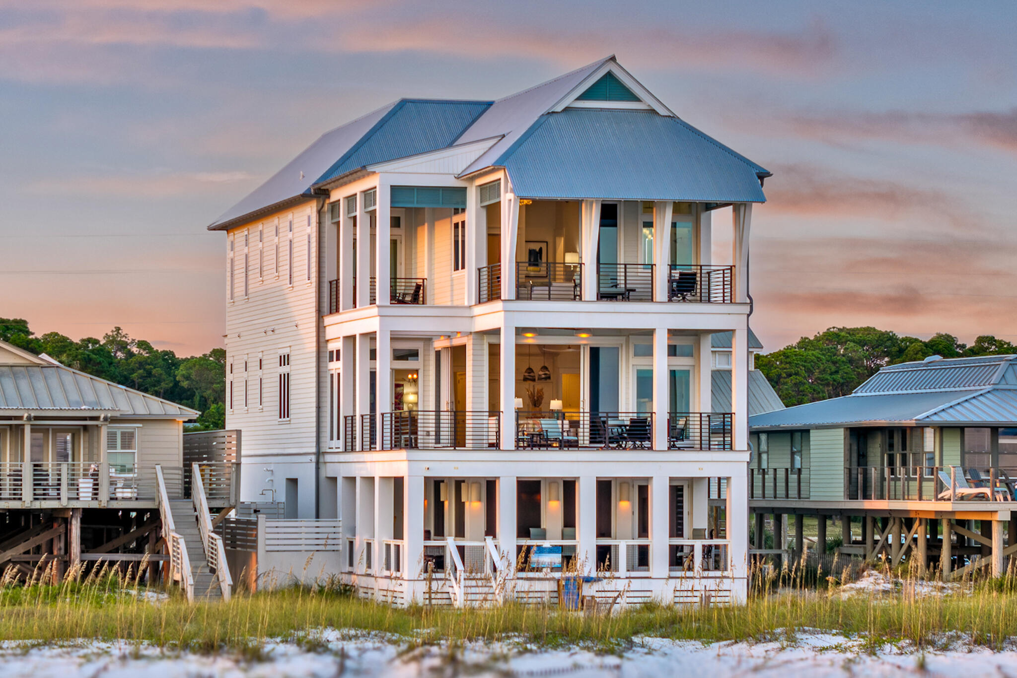 Boundless views and unforgettable beach days define this newly built gulf-front residence designed by Geoff Chick and completed in 2023. This architectural masterpiece rises along the shoreline, where walls of glass frame the ever-shifting colors of the Gulf of Mexico and Oyster Lake. Expansive balconies and a seamless indoor-outdoor flow create a living experience that feels both modern and timeless.

The main level offers a soaring great room where sliding glass walls dissolve into the horizon, a gas fireplace anchors the space, and a quartzite-clad kitchen with a butler's pantry inspires culinary creativity. Gather around the oversized island or take meals to the covered gulf-front terrace where the water provides the backdrop. Beach-level living is equally impressive with a screened entertainment terrace featuring a fire pit, outdoor kitchen with vented grill, and Jacuzzi for sunset soaks. A powder room and outdoor shower add convenience, while private beach access ensures days begin and end in the sand.

Five ensuite bedrooms, including a bunk room, each open to balconies with gulf or lake views. A main-level suite provides accessibility, while the top-floor primary retreat boasts cathedral ceilings, a private furnished balcony, and an ensuite beverage bar for morning rituals. Dual laundry rooms, elevator service to all floors, and abundant storage ensure every need is met. 

Additional features include 12 foot ceilings on all floors, a Tesla EV charger, two-car garage, and a whole-house generator. This masterfully designed gulf-front residence offers an elevated coastal lifestyle, where design, comfort, and nature converge in perfect balance.