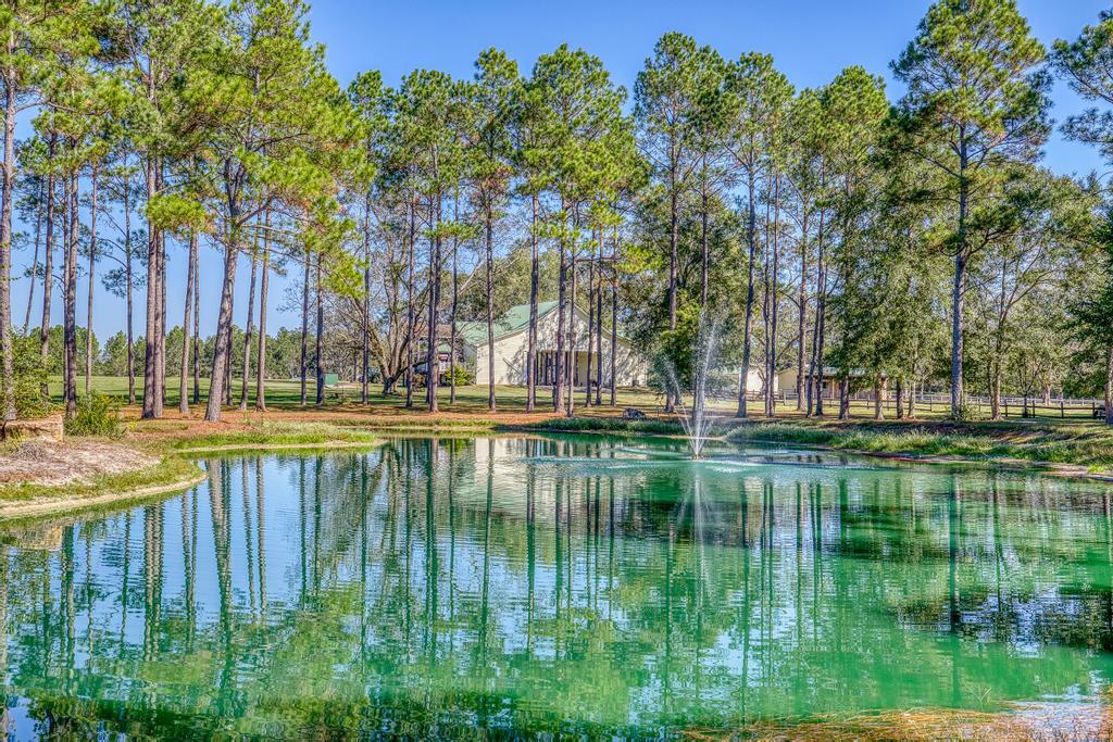 Quailtimber Plantation is a breathtaking 172-acre legacy estate nestled in the heart of Laurel Hill, Florida, where refined rural living meets unparalleled privacy and recreation. Thoughtfully designed for those who value land, lifestyle, and luxury, this rare offering delivers this exceptional property that offers the perfect blend of recreation and versatility, making it ideal for outdoor enthusiasts, hunters, equestrians, or anyone seeking a peaceful rural retreat. The land features a serene fully stocked, spring fed pond, miles of established trails with multiple shooting houses thoughtfully placed throughout the property. This is truly a Hunter's Paradise. Expansive pastures currently support horses, cows, and donkeys. The property is complete with a large custom built horse stable w with 6 stalls, large detached 1200 sq ft storage/workshop, large custom built deer cleaning facility, and a RV site with power. The custom main residence, built in 2007, offers a distinctive unique split-style home connected by a large covered carport. One private wing features a full kitchen and living area, one bedroom, and a full bath, perfect for guests or private living quarters. The primary wing showcases a spacious kitchen open to an inviting living area designed for entertaining, along with four bedrooms, three full baths, and a large flex room that can serve as a game room or an additional living space. Completing the estate is a second residence on the property built in 1960, featuring a full kitchen, two bedrooms, perfect for extended family, caretakers, or income producing opportunities. Quailtimber Plantation is a rare and compelling offering, an elegant, multi-use estate where outdoor adventure, refined comfort and privacy converge. All of this, while maintaining convenient access to Pensacola, Crestview and Destin, makes this property an exceptional opportunity for a private retreat, legacy holding, or an exclusive getaway in the beautiful Florida Panhandle. Hurry!