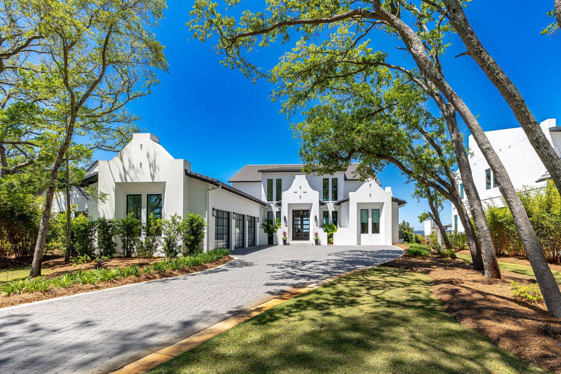 This extraordinary coastal estate is a legacy property sitting on almost an acre with 100 feet of prime waterfront on Choctawhatchee Bay. Boasting amazing year-round sunset views, it has a private pool, dock, and boat slip with lift. This outstanding residence is perfect for hosting lavish parties and entertaining on a grand scale. Built in 2021, it has an elegant white stucco and painted brick exterior. Step through the door to find a breathtaking open floor plan with 23-ft. ceilings and an upper mezzanine. Two stories of floor-to-ceiling glass frame breathtaking bay and sky views while fully retractable doors seamlessly connect the great room with the outdoor lanai. An impressive two-story fireplace emphasizes the visual impact of this soaring space. Reclaimed barn-wood flooring enhance the living area along with reclaimed wood in the beamed ceilings in the living room and primary bedroom. The gourmet kitchen will thrill any chef with its Wolf and Sub-Zero appliances, two dishwashers, two refrigerators, an ice maker, and a built-in Miele coffee system. A pantry and laundry provide further storage space. Casual dining can be enjoyed in the adjoining breakfast nook overlooking the pool and blue bay waters. The first floor includes an expansive primary suite with walk-in closets/dressing room and a spa-inspired bathroom with a garden tub and separate shower. There's also an office with bay views and two guest bedrooms. A floating staircase with a glass-and-brass handrail ascends to the second floor where a theater room and two further bedroom suites are reached from the gallery. This private home sits at the end of a gated tree-lined driveway, leading to a three-car garage with aluminum and glass doors. As well as a heated saltwater pool and spa, this waterfront property has a walk-in sunken fire pit and mature trees in the landscaped yard. The entire home benefits from a water filtration system. The lengthy private dock has ThruFlow decking, a covered boat slip and a cradle lift to thrill any keen boat owner or fishing enthusiast.
