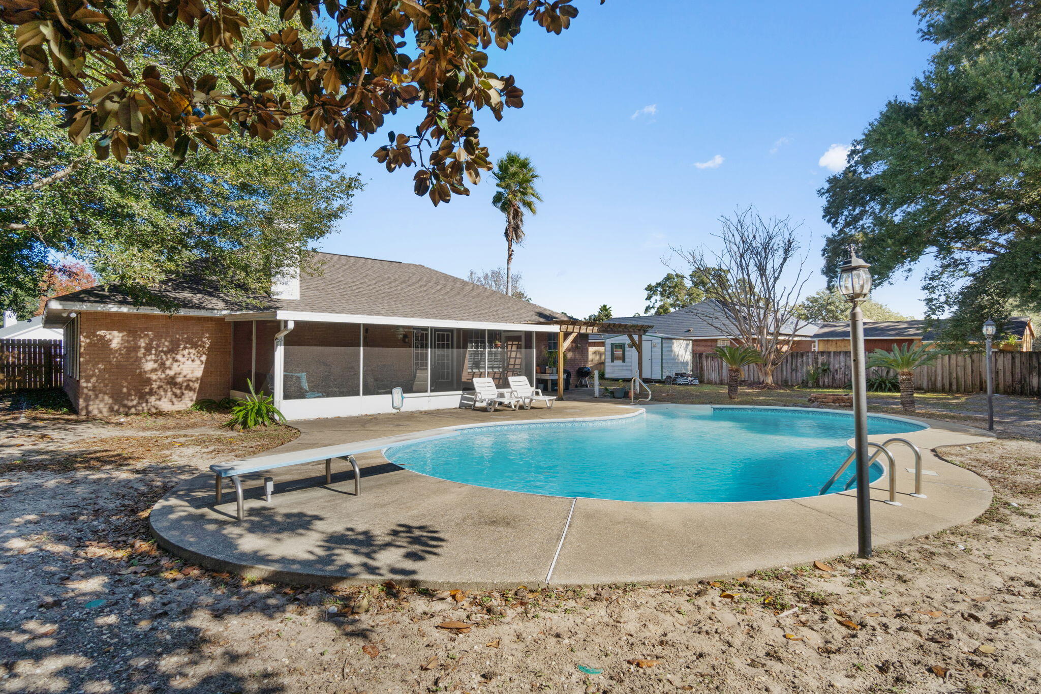 *Pool Home with a 2022 roof!* Situated on a spacious corner lot in Navarre's Spanish Trace Estates neighborhood you're going to love this pool home featuring 3 bedrooms, 2 bathrooms, and 2 additional separate flex rooms (often used as a formal dining room and office/den). Enter in the front door past the tropical landscaping and you'll find the two flex rooms on either side with a great sized living room just past that featuring a corner fireplace and vaulted ceiling. The kitchen has a hop up bar and is open to eat in kitchen space which overlooks the backyard. There is NO carpet in this home, only hard surface flooring! The split floor plan allows for owner's suite privacy with a great sized room and an en suite which has TWO walk in closets, double vanities, a walk in linen closet, private water closet, and a walk in tiled shower. The other two bedrooms are great sized and share a fully renovated guest bathroom! The interior laundry room leads to the 2 car side entry garage. Enjoy the outdoors or entertain with the large screened enclosed patio, a pergola offering additional seating area and a very spacious back yard with beautiful oak trees and featuring a large in ground swimming pool within the fully fenced in back yard complete with an outdoor storage building! Experience the best of Florida living close to Navarre's beautiful Emerald Coast beaches! Roof is 2022 and water heater is 2018.