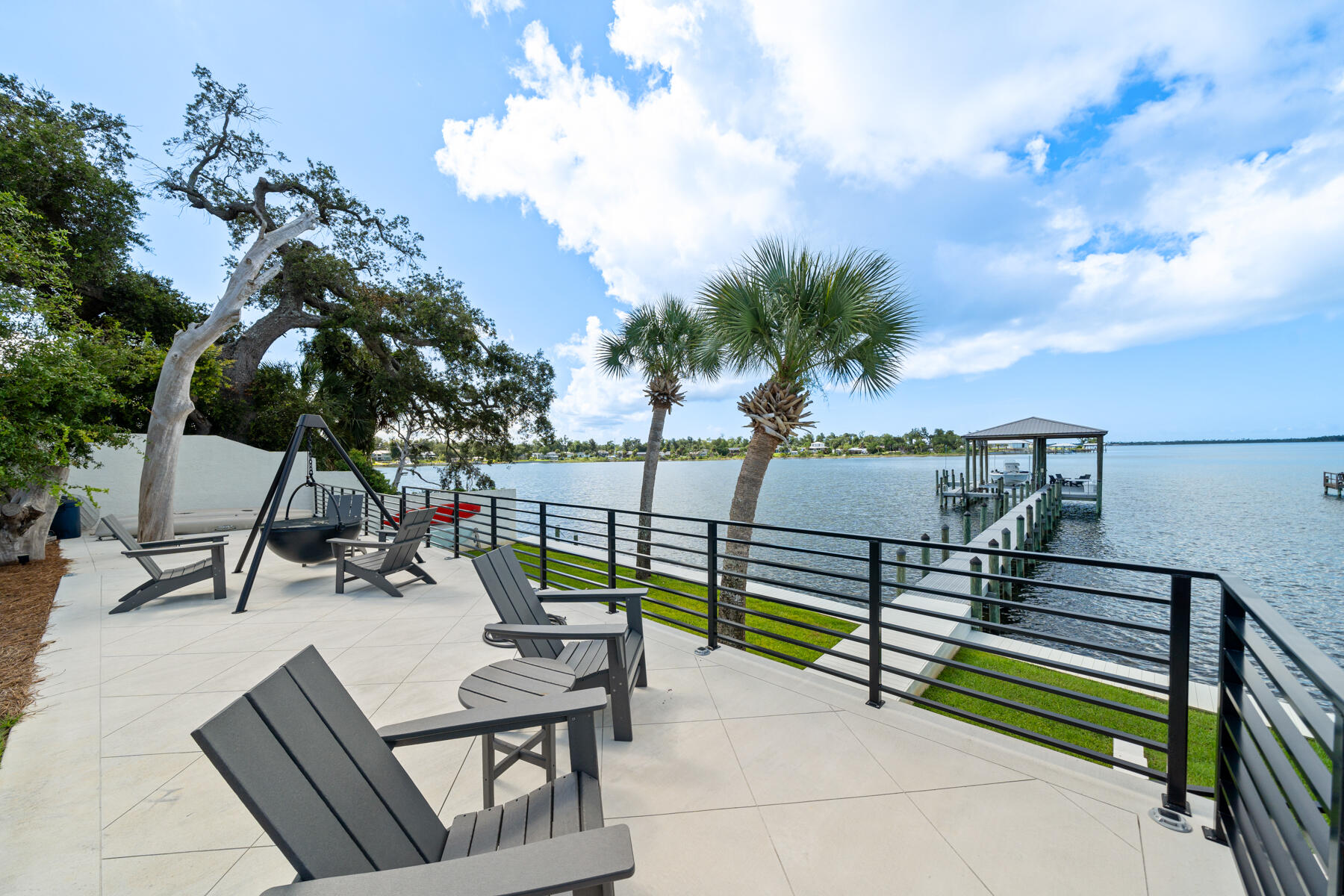PRICE IMPROVED on this exquisite private WATERFRONT estate, where transitional finishes seamlessly blend with modern luxuries. Situated on over half an acre with 100 feet of water frontage, this home offers unparalleled south-facing bay views and breathtaking sunsets. The lifestyle here is all about the water—whether it's diving into the pool after a day at Shell Island or relaxing on the back patio with a year-round sea breeze.

This gated waterfront state ensures ultimate privacy with lush landscaping, a boat dock and lift, pool and 4,189 square feet of living space. Inside, you'll find exceptional finishes, including white oak, oiled-finish hardwood floors throughout, a Chef's kitchen with exquisite water views, and spacious interiors. This home features 3 bedrooms, 4.5 baths, a bonus game room/flex room with wet bar, a 600-bottle, foam-encapsulated and temperature-controlled wine room, and a home office, making it the perfect forever home on the water.

Recently renovated with the highest quality of construction, this contemporary and modern design spans mostly one level, offering expansive outdoor living areas, an incredible boat dock and boat lift, and a luxurious pool. The 2019-built dock is designed for boating enthusiasts, featuring high-end ThruFlow grated decking, a 10k lb Golden boat lift with a covered boat house, low-profile solar lighting, security motion cameras, and ample gear storage.

Upon arrival, a gated entrance with natural native landscaping and the soothing sounds of the Bay welcome you. The outdoor entertaining area includes multiple seating areas, a 36'' Cowboy Cauldron Fire Pit next to the pool, and plenty of space for activities like boating, kayaking, paddleboarding, fishing, and sunbathing. This location is well-known for it's proximity to the new sports complex that residents can enjoy including pickleball, basketball and a dog park. This home is also just minutes from Tyndall Air Force Base as well as a short drive to the World's Most Beautiful Beaches!

As you step into the charming covered entry, you'll be captivated by the meticulous millwork and stunning waterfront views. The great room, with its high ceilings and full-glass windows and doors, leads to covered and open patios where you can enjoy both the pool and the Bay. The Chef's kitchen, located just off the living area, features an oversized island, high end Samsung stainless appliances, and a walk-in pantry. The dining room, open to the living room, connects to a 600-bottle capacity custom wine room, making this home ideal for entertaining on the waterfront.

This estate offers everything Florida's waterfront lifestyle has to offer, making it the perfect sanctuary for those seeking luxury and tranquility. Don't miss this opportunity to live your best life...on the water in Panama City, Florida!