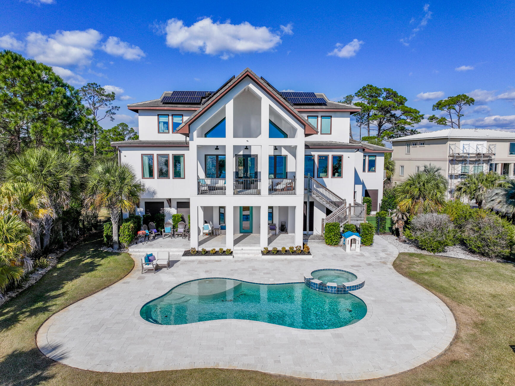 Welcome to your stunning waterfront home and private gated community! You will be amazed at the views and privacy as you drive over the wooden bridge that leads directly to this luxurious 5 bedroom home.  Walking into the home, you will be greeted with your private office with waterfront views, along with a newly added theatre room. There is a half bath and access to the covered patio and heated saltwater in-ground pool and spa. On the main level, there is an open concept kitchen; equipped with custom cabinetry, new tile backsplash, quartz counter tops, gas stove, and stainless steel appliances. The living room, with vaulted ceilings and incredible waterfront views, boats a gorgeous wood fireplace with new tile. The pantry off the kitchen has beautiful custom sliding barn doors, and leads to the laundry room with cabinets, double sink and access to a half bath, and additional bedroom conveniently located on the main floor. The waterfront Master bedroom has a large new spacious walk in closet, fully renovated ensuite bathroom, with a walk in steam shower, tub, and Toto toilet. The upstairs open loft offers a great space for a game room or workout area, with water views on both sides. The two additional upstairs bedrooms are spacious, with gabled ceilings and private en-suite bathroom, both with water views. Additional upgrades include fully paid off solar panels, a new $20k seawall, as well as Tesla powerwall charger in the garage to run major appliances if there is a power outage. This exquisite home is even more remarkable in person!