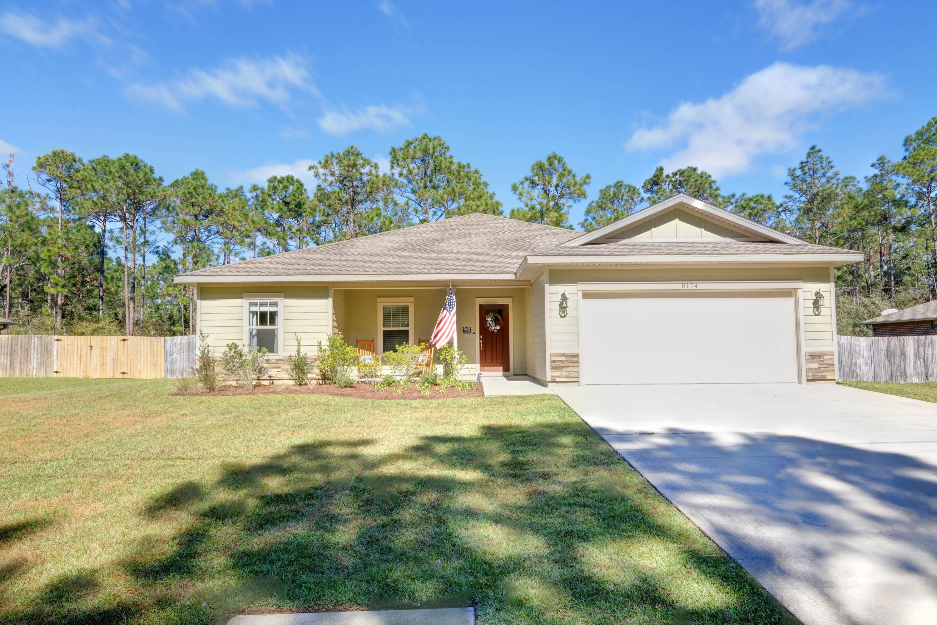Welcome to this exceptional craftsman 4 bedroom/2 bath home by a quality local builder located in a prime Navarre location on a quiet street and a massive lot! Clad in durable cement fiber board with an architectural shingled roof, this exquisite property has all the space and updated features you've been searching for. Walk up the driveway and after passing the adorable covered front porch you'll love the formal entryway boasting a trey ceiling and crown molding. The open concept living room and kitchen feature thick quality wood laminate flooring throughout with oversized custom cabinetry, a separate pantry, granite countertops, and stainless appliances with a fantastic and expansive kitchen island. There is a designated dining area with an additional trey ceiling, which leads to the private master suite also adorned with a trey ceiling and crown molding. The owner's bathroom is a retreat with double granite vanities with undermount sinks, framed mirrors, a walk in closet, and a beautiful fully tiled walk in shower with accent tile and a glass door. The other 3 spacious bedrooms are located on the other side of the house with ample closet space, as well as a shared bathroom with the same quality finishes as the master bath and kitchen. The transom windows over the hall entryways provide a high end custom touch. From the entry hallway you'll find a perfect drop zone leading to the interior laundry room with tiled floorings, and the two car garage. Outside you'll find a massive covered back patio overlooking the spacious fenced in backyard completed with an irrigation system on a well, but it doesn't end there because the property line actually extends far past the fence measuring almost half an acre! This home comes with fabric shield hurricane shutters and a termite bond for peace of mind! With a short commute to surrounding military bases and only minutes from Navarre Beach and local shopping and community parks, don't delay in making this gem your own!