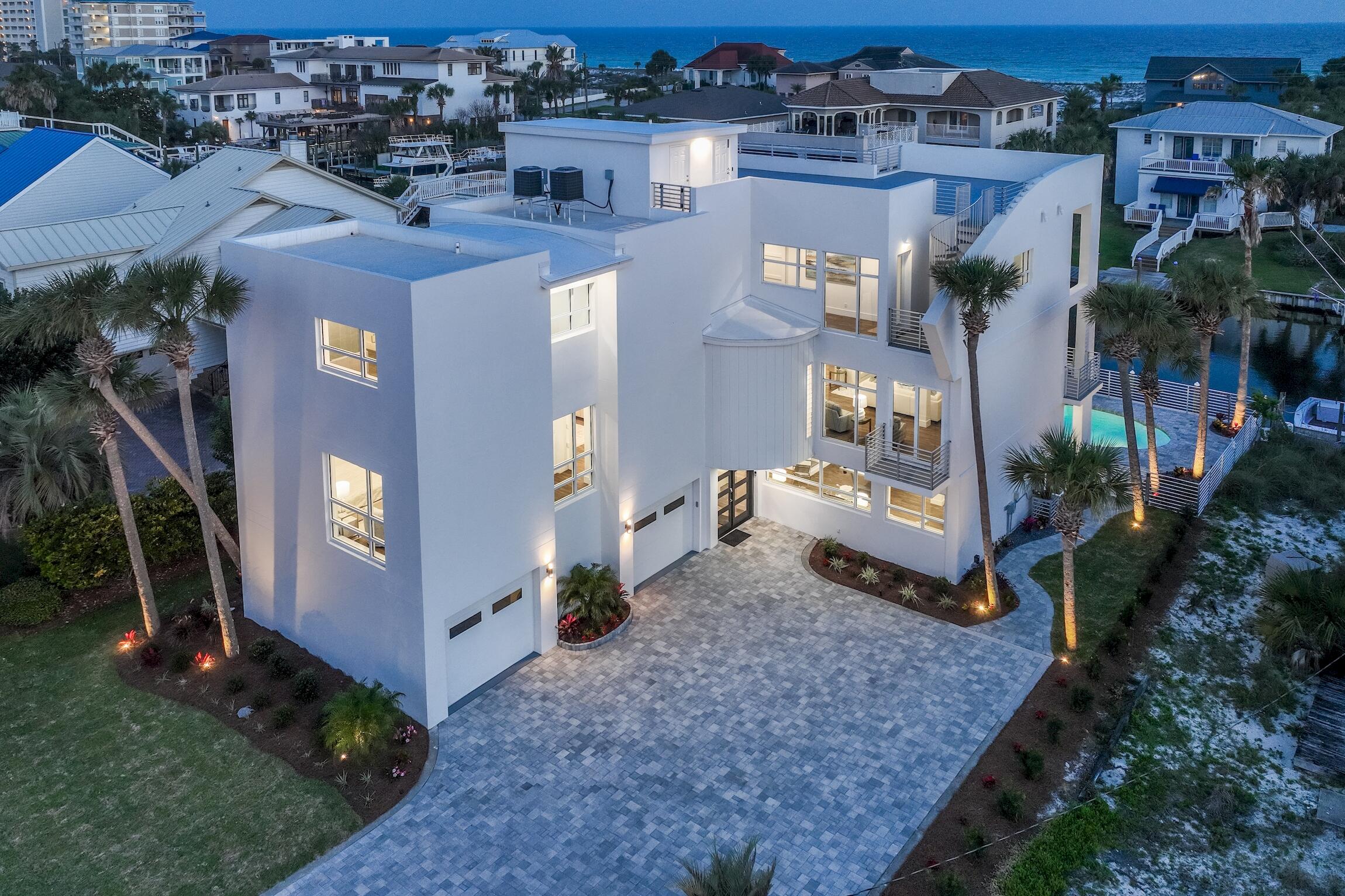 PRICE REDUCTION ! Nothing spared in this completely renovated concrete and steel constructed gorgeous 6,000 + sq foot home on Holiday Isle.  Completely furnished by Risa with designer pieces and  luxury lighting, this stunning home will dazzle you with natural lighting from tall windows and high ceilings.  With 80 feet of dock on a deep water canal that leads to the bay and the Gulf of Mexico, plus a boat slip that will host a midsize boat, this modern paradise beckons the avid boater.  Framed by the new dock on 2 sides, the pool suggests a refreshing plunge after a wonderful day of deep sea fishing.  All 3 stories have a master bedroom with the ground floor offering a ''captain's quarters' that includes a master bedroom, kitchen area and living space with a pool table. In addition to it's spectacular visual appeal, this home provides the most convenient living circumstances which include oversized closets in the bedrooms, a workroom between the 2 garage spaces, a central vacuum system, instant circulating tankless water heaters, a storage room on the roof top deck for your outdoor furniture during inclimate weater, and two laundry rooms, one on the first floor and one on the 3rd floor.  Enjoy wonderful weather out on your roof top deck that expands across the whole house and is accessible by the spiral staircase or the elevator.  With expansive 360 degree views that include the beautiful emerald green waters of the Gulf of Mexico, friends and family will seek out this incredible refuge to relax and mingle.  Water and gas hookups on this roof deck offer the potential for a really fabulous outdoor kitchen to enhance your entertaining.  Holiday Isle association provides private deeded beach access to all homeowners and guests.  The photos of the 74 foot Viking parked out back references the docking capabilities of this home.

Following is a list of new or replace items:
showers,
tubs
cabinetry,
entry doors,
outdoor pavers,
pool pump and filter,
stucco done by Christian Perry,
quartz countertops,
sinks, Delta faucets and hardware,
tile floors that look like hardwood,
Viking appliances,
A/C condensors,
elevator,
landscaping, 
sprinklers,
exterior lighting,
instant circulating tankless water heaters,
liquid applied urethane roof deck,
wired for wireless access points on all 4 floors, 
new dock with synthetic decking.