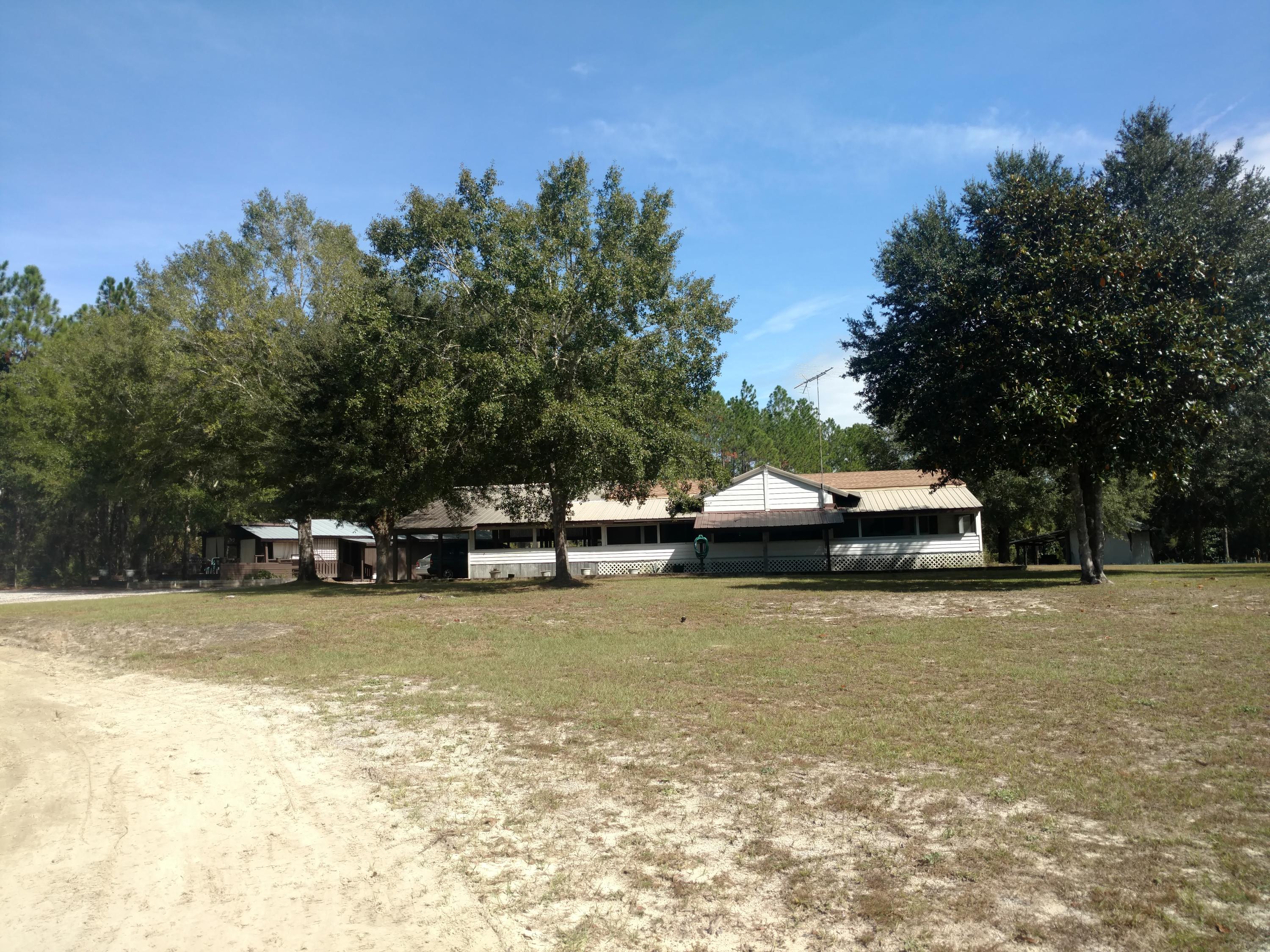 Truly a ONE-OF-A-KIND OPPORTUNITY.
Five Acres of Land plus an immaculate 3Br/2Ba Manufactured Home with attached carport & decks. Detached Garage, workshop, separate laundry area, & Upstairs Garage Apartment with Full Bath & kitchenette. Unique outdoor pavilion which is a great place for cook-outs, entertaining & more. Additional building for workshop, storage, carport areas & unfinished upstairs. Several outbuildings for gardening or storage. Approx. 2.5 to 3 acres is cleared & the remainder is wooded with small running creek. Adjoins the Windswept Dunes Golf Course community. Central to Walton & Bay Counties. Less than 30 min to Beaches. This is a property has had a lot of love & offers so much potential - residential or investment. Truly a One-of-a-Kind Find for this Area.