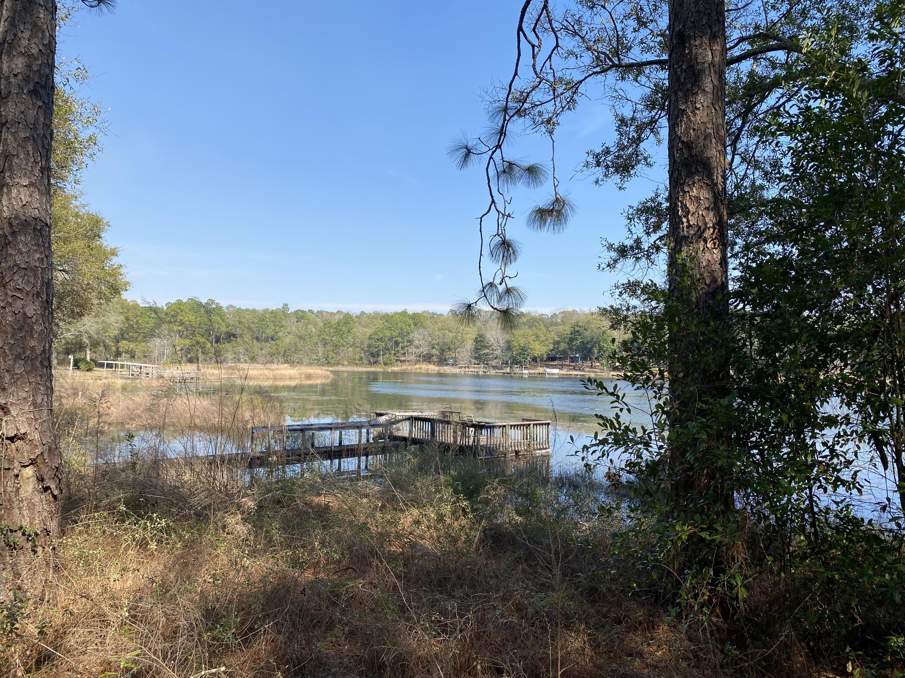 Your Lakefront Dream Begins Here: Step into a world where nature's beauty unfolds on the shores of Lake Holley. This Beautiful waterfront property, with an impressive 298 feet of lake frontage, is a rare find in DeFuniak Springs, Florida. Picture your future home amidst the grandeur of towering trees, with a gentle slope leading down to the water where bass and bream play. Although the land hosts a mobile home and storage structure, the real treasure lies in the endless possibilities to create a magnificent lakefront estate or two separate havens of peace and privacy. Enjoy exclusive amenities like a private community boat landing and dock, all within a secluded setting that promises a lifestyle of relaxation and recreation. There is an older mobile home and storage shed on the property but it is being sold ''as-is'' and is being given no value.
