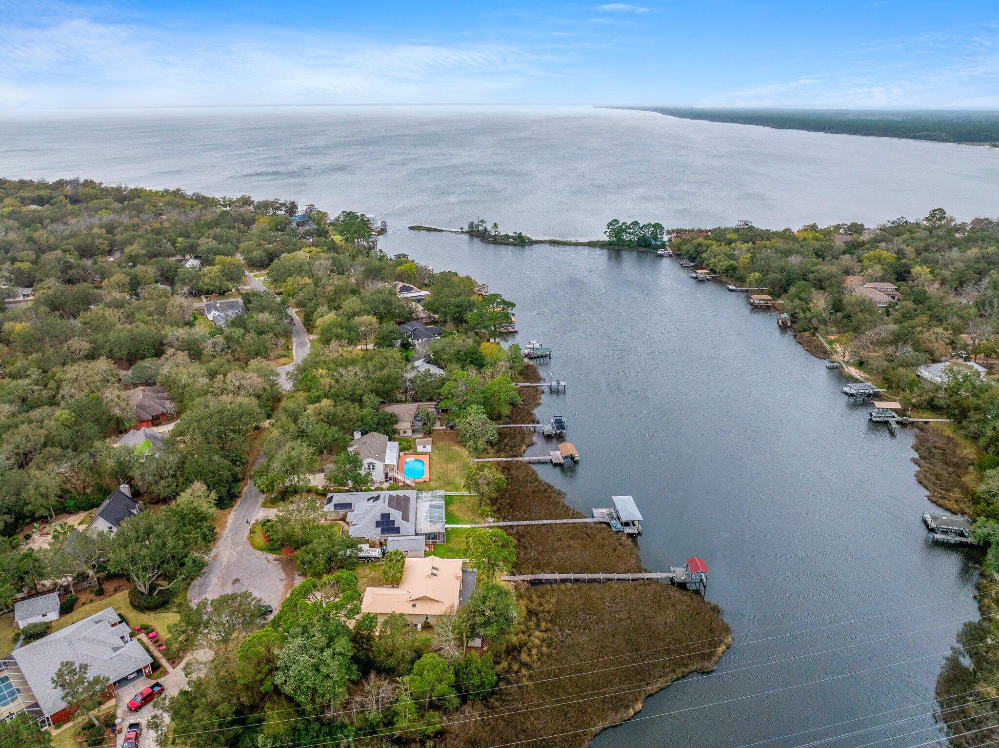 PRIVATE BOAT DOCK & BOAT LIFT!! Elegantly poised on the serene banks of the Bayou with direct access within minutes to East Bay Waters, this ranch-style residence embodies the essence of waterfront living. Boasting panoramic views from the living room, kitchen, master bedroom, and office, this home offers an unparalleled connection to the water. The property features a private pier leading to a personal boat dock equipped with a new lift system and remote control, ensuring immediate access to open waters. A new composite deck was built in January 2023 making this outdoor experience ideal for boating enthusiasts and those that like to spend their time outside. (see a full list of upgrades below) This home is nestled at the end of a cul-de-sac in the tranquil Mossy Cove neighborhood, this property promises a peaceful lifestyle with no HOA fees. Occupying a generous half-acre lot, this home is a haven of privacy for those seeking a quiet waterfront living experience. With this new Generac Generator installed in 2022, this home is protected as it will deliver power directly to your home's electrical system in the event of a storm. It is equipped with two liquid propane tanks that were installed as well for the generator (only). Home has a built in sprinkler system with a pump serviced by its own well and a metal roof.  

Its thoughtful split-level design secures the utmost privacy for the master suite, complete with an en suite bathroom separate from the other two guest bedrooms and guest bathroom. Recent enhancements totaling over $34,000 elevate this living experience, including:

- New Deck with composite flooring and updated support (2023) - $14,000
- Generac Generator (2022) - $12,332 (including two propane tanks)
- Boat Lift with stainless steel cables, new belts, and remote control (2022) - $1,880
- Frigidaire Microwave Wall Oven Combo (February 2023) - $3,100
- Refrigerator (January 2021) - $2,674.00
- Dishwasher (June 2022) - $761.95
- Hot Water Heater (2021)
- Garbage Disposal (2022)
