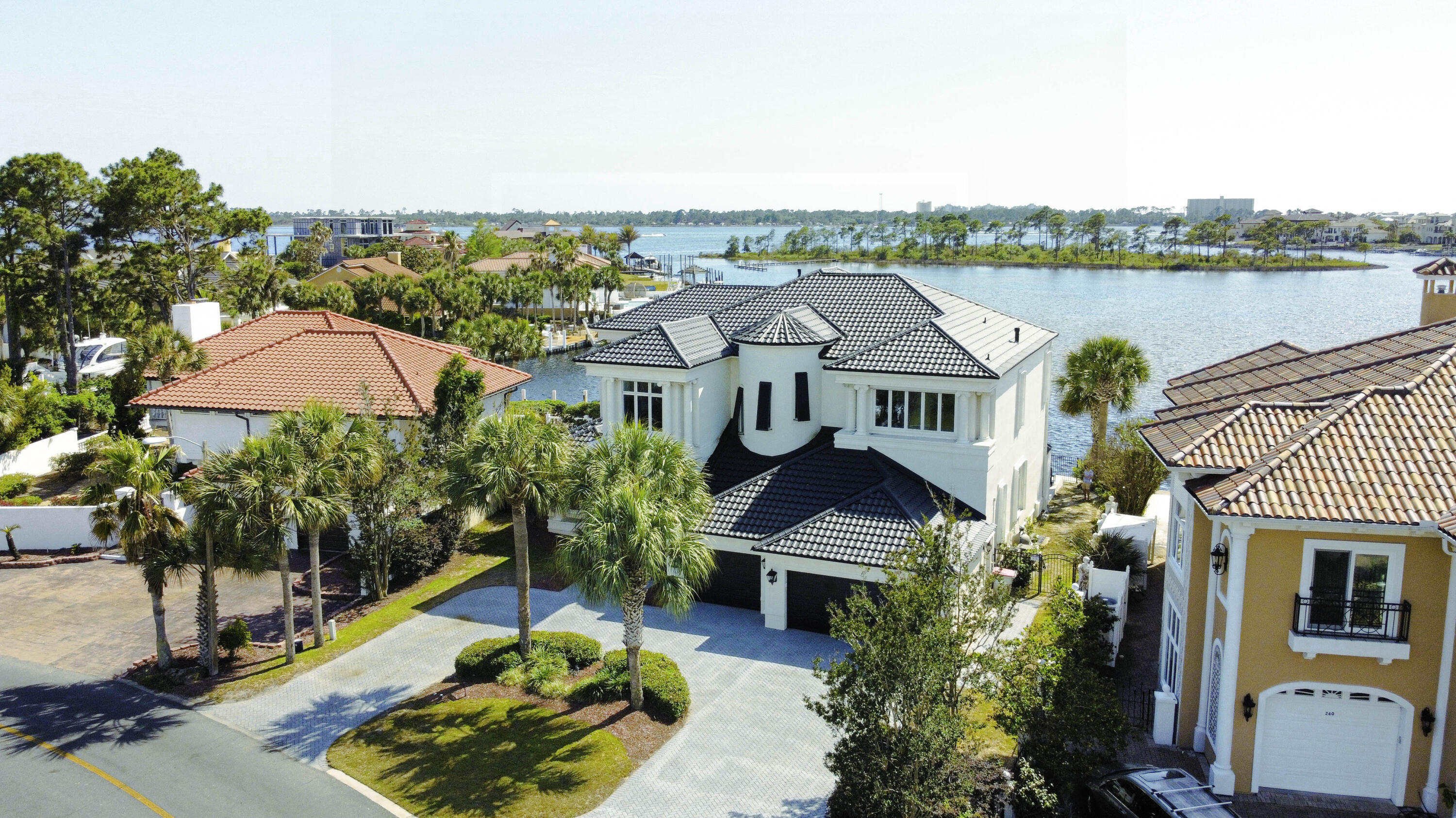 This passage describes a modern American home designed to evoke a sense of wonder, with exquisite finishes and breathtaking views of the Grand Lagoon from all angles. The property has 106 feet of deep-water frontage, a backyard dock, and a heated pool that offers indoor-outdoor living. The owners recently installed a changing room for your convenience when you are lounging around at the pool. The chef's kitchen features a waterfall black-honed granite center island and other high-end features like double ovens and a subzero. The main floors are adorned with marble of various depths and colors, while the master and second levels have contrasting black wood floors. The 3-car garage provides ample parking space and a circle drive with room for more parking as needed. Upstairs is a second master with a balcony, a game area, and additional bedrooms and guest suites with sitting rooms, balconies, and custom closets. This property's location is in the gated community of Bay Point, a guarded community with easy access to St Andrews Bay and the Gulf of Mexico. The site is ideal for fine dining, yachting, tennis, and golf. If you like to get involved in social clubs, we have so many to choose from, like The Yacht Club, Bay Point Women's Club, etc. This community is a lifestyle, and you will love all it offers. The owner replaced the roof recently, installed new hurricane shutters on the outside windows, and installed a whole house generatorso many additions since they have owned the property