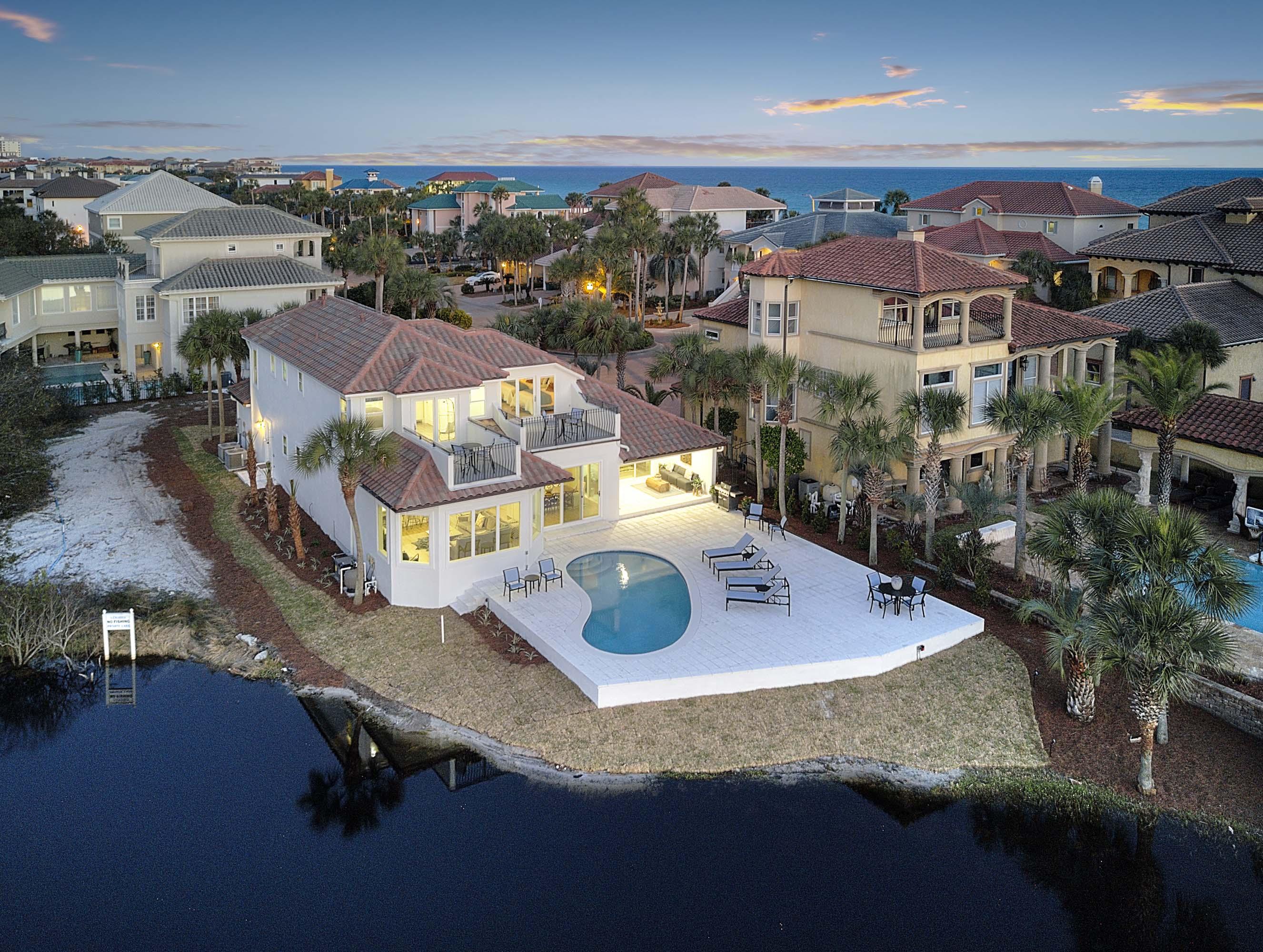 Modern elegance meets artful coastal contemporary design in this awe-inspiring beachside lake front residence ideally located two tiers off the Gulf of Mexico in the gated community of Destiny. In early 2018, this home was another remodel completed by Coastline Luxury Home whom finely appointed the home with professional interior design & furnishings. This home is masterfully configured featuring 5 bedrooms (including a 6th bunk room), 4 full bathrooms and a large open floor plan with clean lines and pristine lake vistas. This rental machine presents exemplary investment opportunity with over $200,000 in projected gross annual rental income for 2019. Upon entering the foyer, a wall of floor-to-ceiling windows spanning the South elevation allows an abundance of natural light to cascade into the main living area perfectly framing a western elevation defined by serene lake frontage and gorgeous evening sunsets. The designer kitchen is outfitted with beautiful  floor to ceiling custom shaker cabinetry, stainless steel appliances including a professional grade gas cooktop, Bosch dual convection ovens and wine cooler. A full size refrigerator & freezer allows for more than adequate fresh food storage. The kitchen also pairs utility with beautiful aesthetics including quart countertops, an ample sized island with a gourmet under-mount sink as well as ample storage in the separate pantry space. The covered rear patio is perfect for entertaining and features both covered and uncovered living space all of which is focused over the fabulous outdoor patio and in-ground pool area which opens freely to the expansive lake views. The Master suite occupies it's own private wing and features  gorgeous decor, beautiful views over the pool & lake area, large walk-in closet with built in shelving as well as a spa like Master bath complete with dual vanities, private water closet, free-standing soaking tub and large walk-in shower featuring a suspended glass surround, pebble flooring as well as floor to ceiling tiled accent walls. Other notable features of this property include: custom designer lighting, ship lap accents throughout, security system with multiple surveillance zones, custom window treatments including electronic window shades & plantation shutters as well as an ample size two-car garage. This home is the ideal property as it is fully transitional & highly functional as both a primary or secondary home as well as a top producing luxury vacation rental. Centrally located, this property is in very close proximity to beach access as well as the exclusive amenities offered in Destiny which include a private fitness facility, community clubhouse, large community pool & spa, professional tennis courts and proximity to world class shopping, dining and entertainment