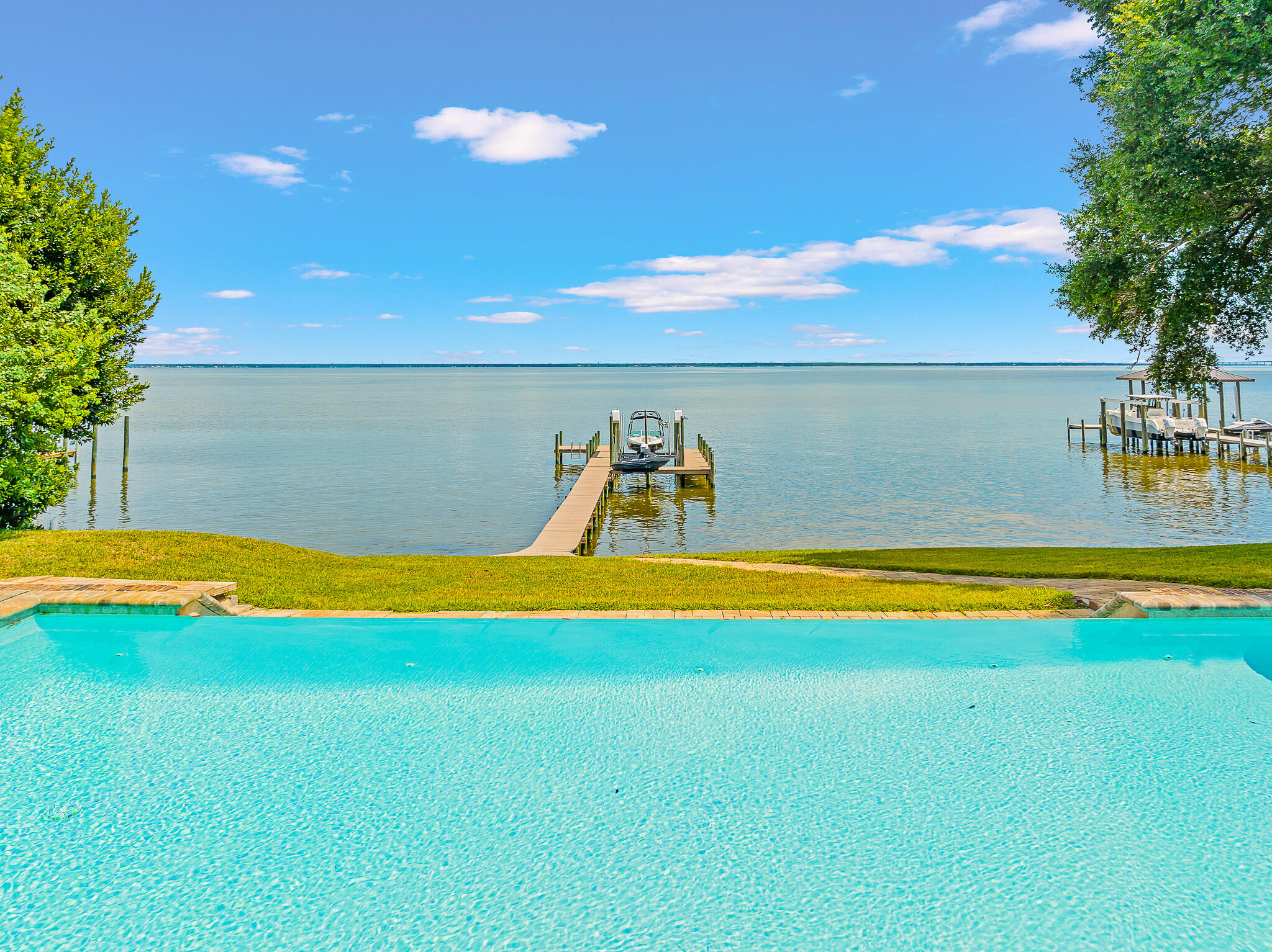 100 feet of Bay frontage at one of the highest points in Destin with this 2013 built
home! This spacious, meticulously maintained single-level brick home on an estate-sized lot
provides the ultimate setting to take in the bay views and breezes, complete with a dock, boat
lift and jet ski lift. Thoughtful outdoor living space includes a covered patio and wide sundeck
surrounding the pool. Enter the long driveway under a canopy of shady oak and magnolia trees
to this four bedroom, three and a half bathroom custom home, built less than ten years ago. The convenient floor plan offers an open-concept kitchen, living room and dining area with bamboo
wood flooring framed by sliding floor to ceiling glass doors, plus an office and heated and cooled
bonus room and garage with epoxy flooring.
This versatile neighborhood and location is ideal for both families, retirees, or a second home retreat. Some photos show virtual staging.