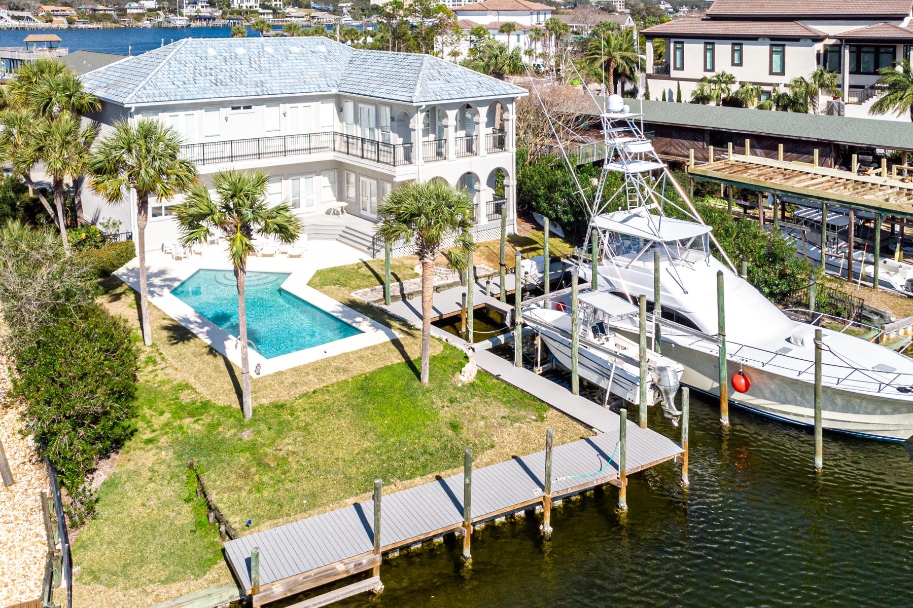 Positioned at the intersection of two canals, this boater's respite on Holiday Isle beckons the fisherman at heart with two 50' boat slips, palm-lined swimming pool, and stately facade. The improved  boating maneuverability possible at this location is a rare find on deep water.   512 Norriego is located in close proximity to the sandy shores of Destin's coveted gleaming white beaches with gated access for Holiday Isle owners and guests. This one-owner home is open, spacious, and inviting, an ideal canvas for your personal touches. It allows plenty of privacy with five bedrooms, including a bunk room with a private bath. The second-floor master suite and personal deck is situated perfectly for views of the canal. If being surrounded by water isn't enough, the master bath invites more relaxation with a jetted tub, separate shower, double sinks, and a large walk-in closet. Pull into your two-car garage and soak up all that the Destin Harbor has to offer by boat, including deep sea fishing, Crab Island, and exquisite restaurants. This home invites easy living on the water from sunrise coffee to sunset cocktails, where you can simply step out onto your lush lawn surrounded by a full size pool and the gentle whisper of the sparkling Holiday Isle waters.