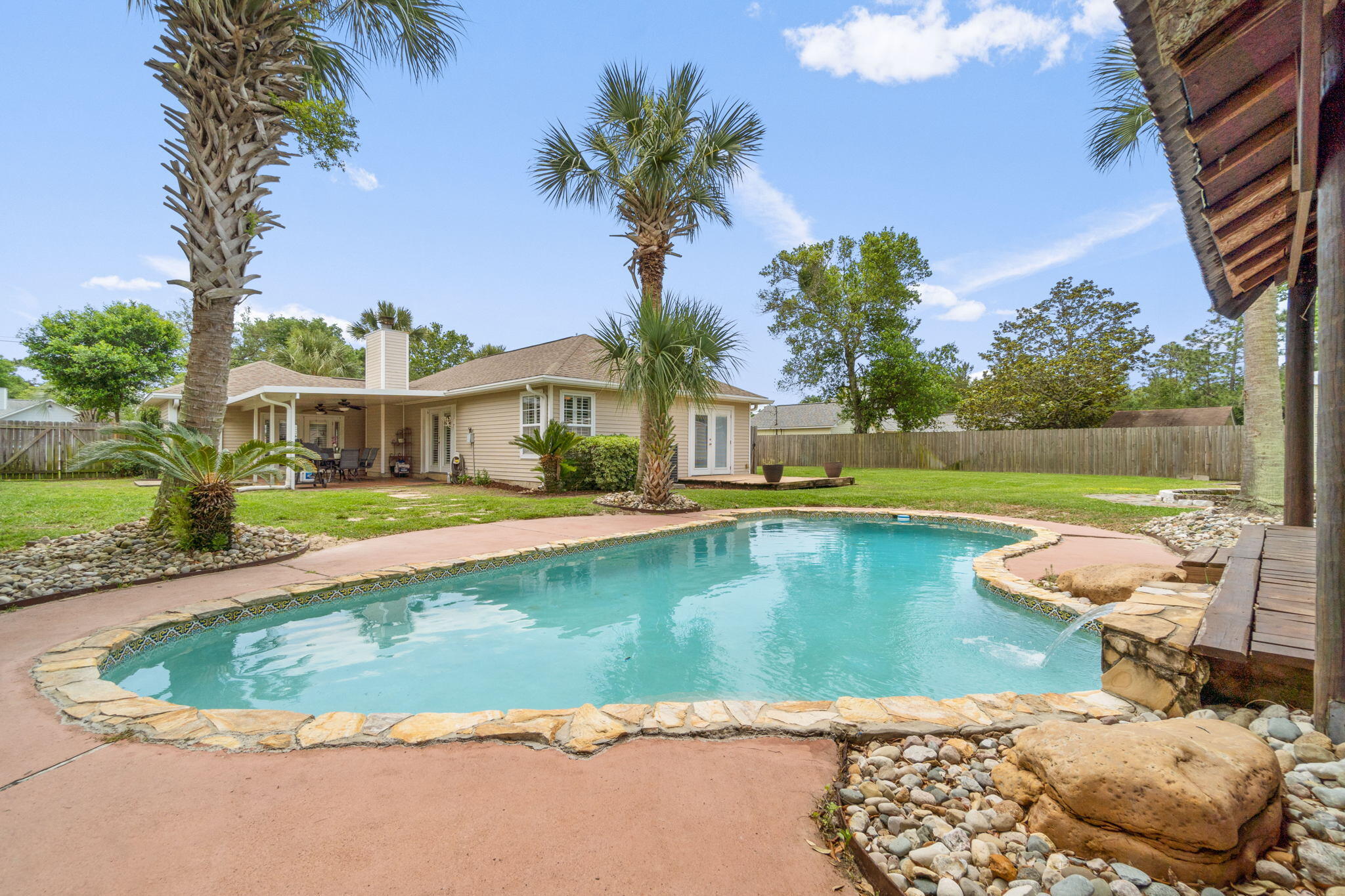 Entertainer's Dream: Paradise (and fun) awaits in your own backyard! Located in the popular area of east Navarre with a quick commute to Hurlburt Field and less than 10 minutes to Navarre Beach's emerald green waters, you'll find this uniquely charming and lovely POOL home that you are sure to fall in love with. The oversized circular drive provides plenty of room for parking, and the quiet street at the back of East Bay River Estates gives you the tranquility you've been searching for with no HOA fees. Inside you'll be smitten with the unique lighting fixtures, ceiling shiplap, and crown molding; and you'll find a convenient split floorplan and a massive living room perfect with tile floor throughout (no carpet!). The master bedroom boasts soaring cathedral ceilings with plenty of room for your king sized bed, and a lovely double vanity with granite counters in the bathroom as well as a walk in closet. Like the large family room, the kitchen is another oversized room featuring a hop up bar and Corian countertops, plenty of space for your large dining room table, a sitting area, a lovely wood burning fireplace, recessed lighting and more of that charming ceiling shiplap! The kitchen has stainless appliances and walking out to the side door is a Pinterest worthy mud room space. There are french doors with plantation shutters leading from both the family room and the kitchen that open onto the large covered patio and from there stone steps lead you to your very own backyard tropical oasis! The in-ground gunite pool is a showstopper in itself with a waterfall and palm tree lined perimeter, but what truly makes it an entertainer's dream is the massive tiki hut/pavilion overlooking the pool. However, it doesn't end there. You'll find a fantastic firepit, a HUGE workshop/man cave, and an oversized detached garage. For the cherry on top the roof AND water heater will be replaced prior to closing, the HVAC was replaced in 2016, and the septic was just pumped in January 2022. Do not delay on making this gem your own and enjoy the very best of Florida living!