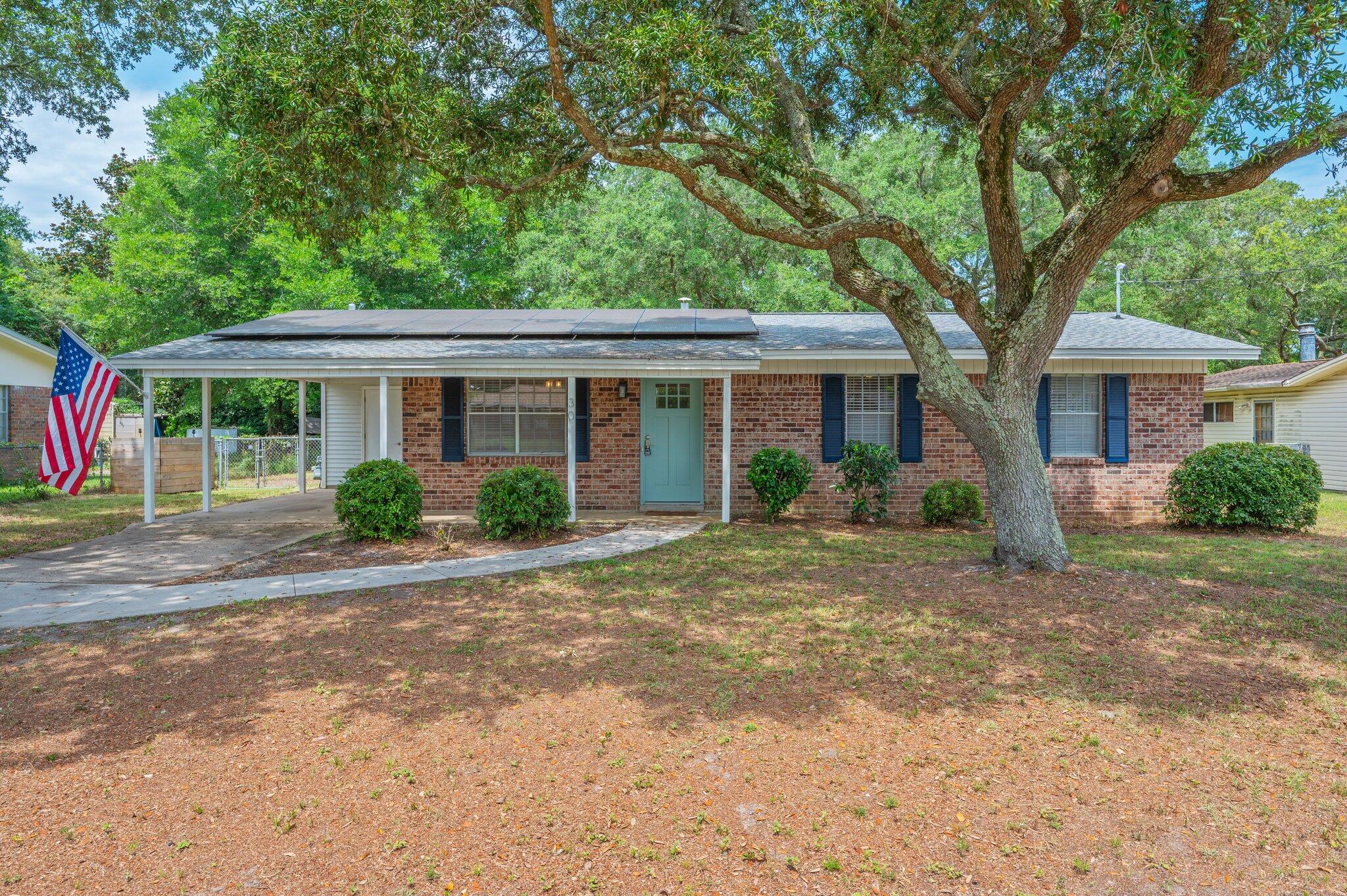 Welcome to this beautifully renovated single-story, three-bedroom, two-bath brick home located in the heart of Fort Walton Beach. Step inside to find luxury vinyl plank flooring throughout and elegant custom molding in the entryway, living room and hallway. The updated white kitchen features stone countertops, stainless steel appliances, and built-ins, opening to a separate dining room accented with a barn door that leads to a mudroom and laundry area—both offering additional custom built-ins. Enjoy modern comforts with ceiling fans, a spacious guest bathroom with a large vanity and custom lighting, and a luxurious tile walk-in shower in the master suite. Natural light pours through the home, creating a warm and inviting atmosphere. Monthly electric/solar fee applies. Step outside to a backyard oasis with a covered patio adorned with charming Edison lights, mature trees for added privacy, and a storage shed. A front carport and ample additional parking make this home as functional as it is stylish.
