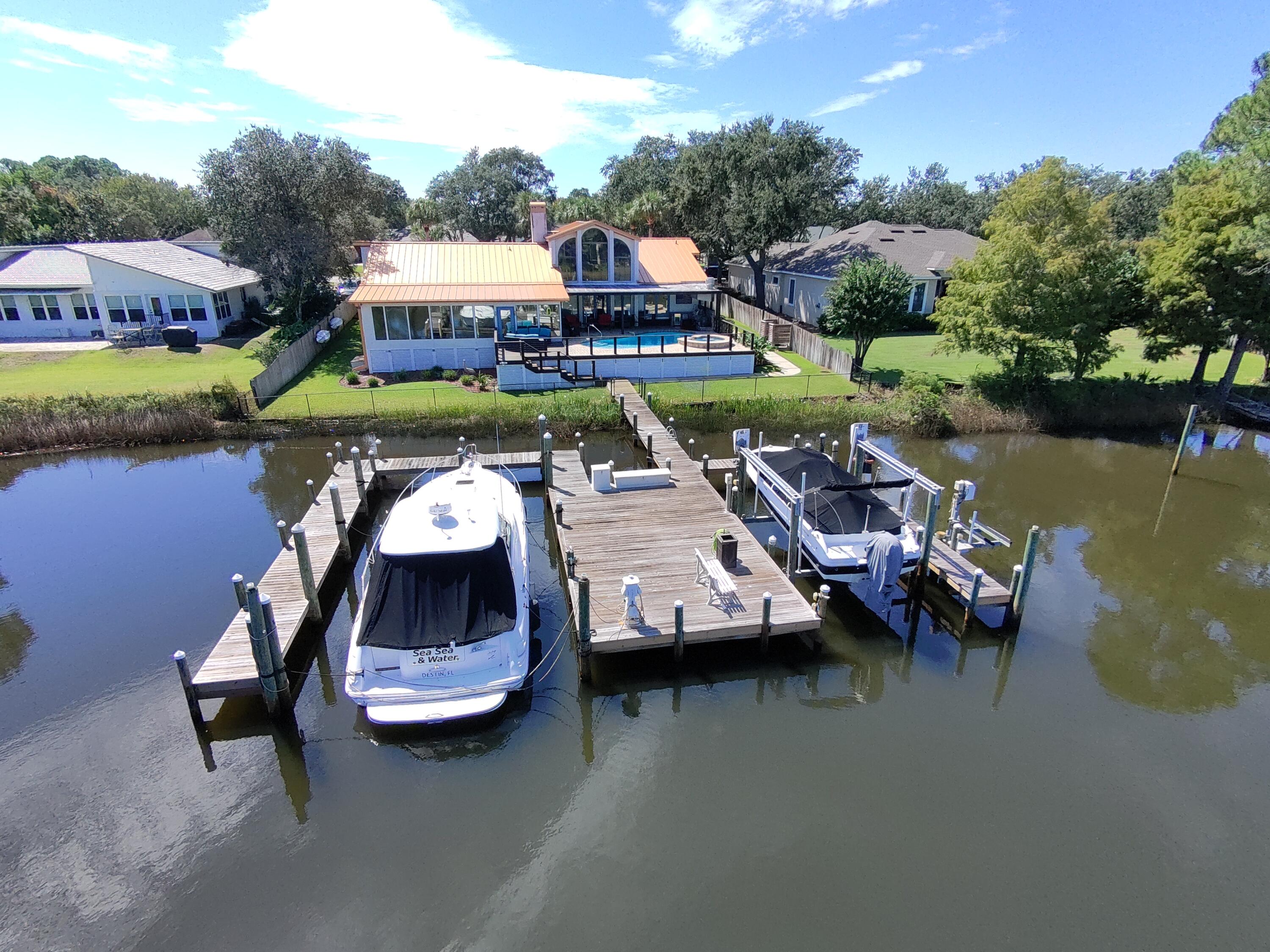 This exceptional home offers deep-water moorage and 100 feet of waterfront on Indian Bayou. Enter to a great room with a stunning 28-foot cathedral ceiling and large windows showcasing beautiful water views.
The gourmet kitchen has been fully renovated and features two islands—one with a copper apron sink—along with granite countertops and custom cabinetry. High-end appliances include a Dacor under-counter microwave, Wolf gas stove, double oven, warming drawer, and a hidden fridge with freezer drawers. The open layout connects to a formal dining area and an office with built-ins.
Relax in the family room with water views, a gas fireplace, and a custom media center. The fully screened lanai features a resurfaced heated pool and hot tub, perfect for year-round enjoyment. The pool is equ equipped with multicolor LED lights, creating a stunning atmosphere for evening gatherings. Adjacent to the pool is a summer kitchen designed for entertaining, featuring a mini-fridge and a premium grill, making it easy to host friends and family.
The master suite offers water views, a sitting room, and a luxurious bath with double vanities, a large shower, a Jacuzzi tub, and two walk-in closets. Two additional bedrooms and baths are located on the opposite end of the home.
The boat dock has two large slips and can accommodate a 50' x 20' boat with a lift and a jet ski lift. Additional features include a new commercial metal roof, water softener, security system, climate-controlled garage, weatherproof back deck, fully fenced yard, generator, and both gas and electric water heaters. This home is perfectly situated in central Destin, offering convenience and luxury. Don't miss out!