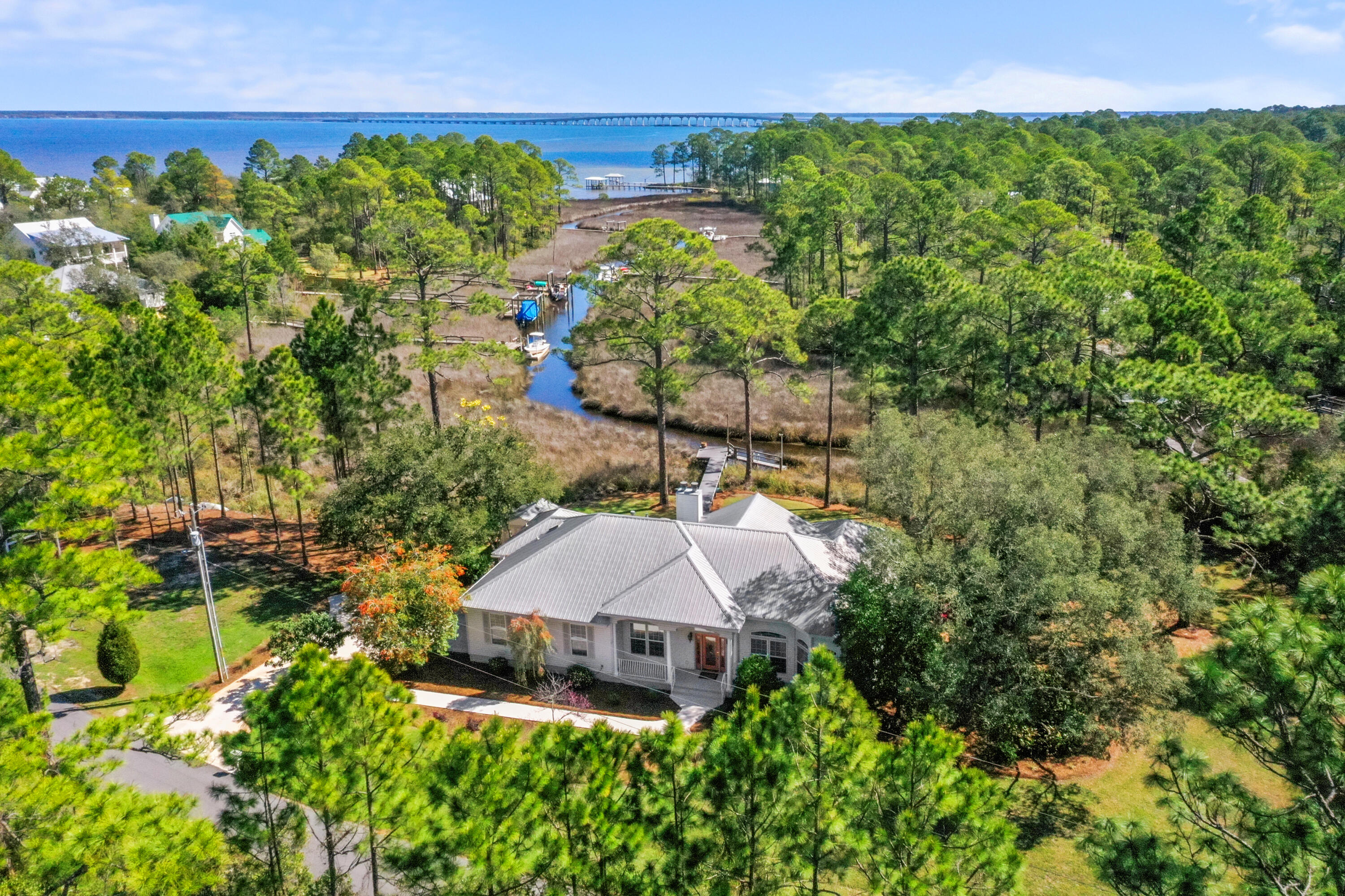 NEW PRICE! This rare 1.2-acre waterfront property is a truly distinctive navigable waterfront setting with sweeping views of a state protected estuary and Choctawhatchee Bay.  Here is a unique blend of natural beauty and privacy within the quiet upscale bay front community of Bay Pine Shores with paved Cul de sac streets.  The 325 ft. wide property provides privacy and has 230 feet of very navigable waterfront along Gurnee Creek with private dock for cruising into the bay and onward to the gulf for all types of water recreation and fishing. The owners obtained a state permit for an additional boat dock and lift and there is ample space to add a private pool and a carriage house.

This very thoughtfully updated, meticulously maintained custom-designed home has soaring ceilings, spacious, flowing living areas with scenic water views and outdoor connectivity from every room to porches and a large covered, screened porch.

The location of this home is just 4 miles from Gulf beaches, state parks, all that Scenic HWY 30A offers and close to nearby shopping, dining and Ascension Sacred Heart Hospital.
 A spacious, covered screened porch also captures the panoramic views, overlooking the peaceful setting surrounded by mature oaks, magnolias, azaleas, and camellias that create a quiet, park-like landscape.
Property upgrades include hardwood floors, a new guest shower, updated PEX plumbing, and freshly repainted walls and cabinets throughout, and feature a 40-year steel roof, an oversized garage, and generous driveway parking. A second large driveway accommodates a camper or boat, and an additional Florida Dock Permit offers the opportunity for a second dock and boat lift, if desired.
Ideally located just minutes from the Gulf beaches, Scenic Highway 30A, state parks, marinas, shopping, dining, and entertainment, and with convenient access to healthcare including Ascension Sacred Heart Hospital, this property offers a rare balance of waterfront privacy and everyday accessibility.